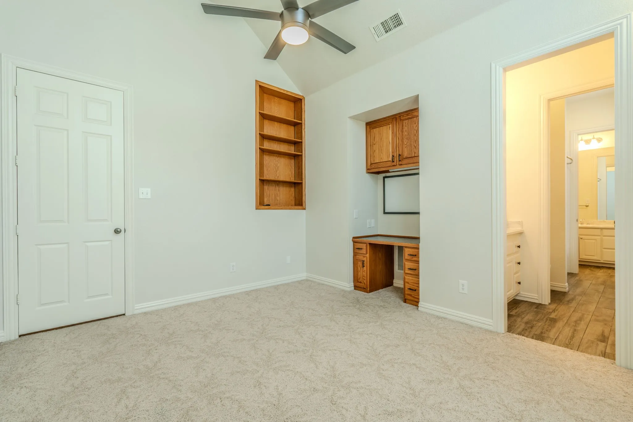 Another view of Bedroom 2 with built-in desk, cabinetry, and an ensuite bathroom.