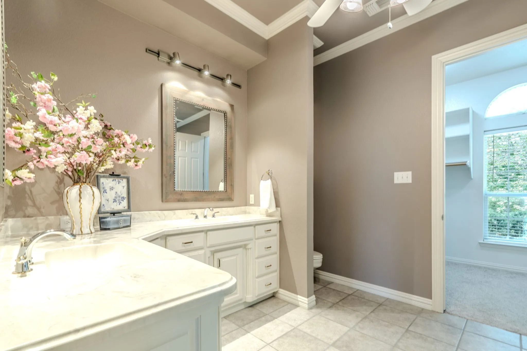 Primary bathroom with dual sinks, beautiful cabinetry, crown molding and decorative lighting.