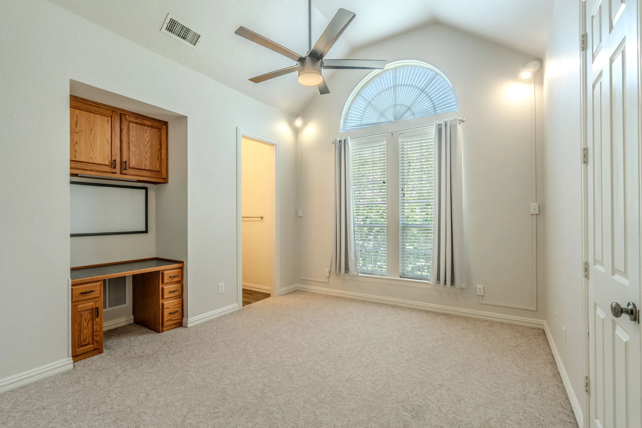 Bedroom 2 with built-in desk, cabinetry, large windows with natural light, fun, decorative lighting, walk-in closet, and an ensuite bathroom.