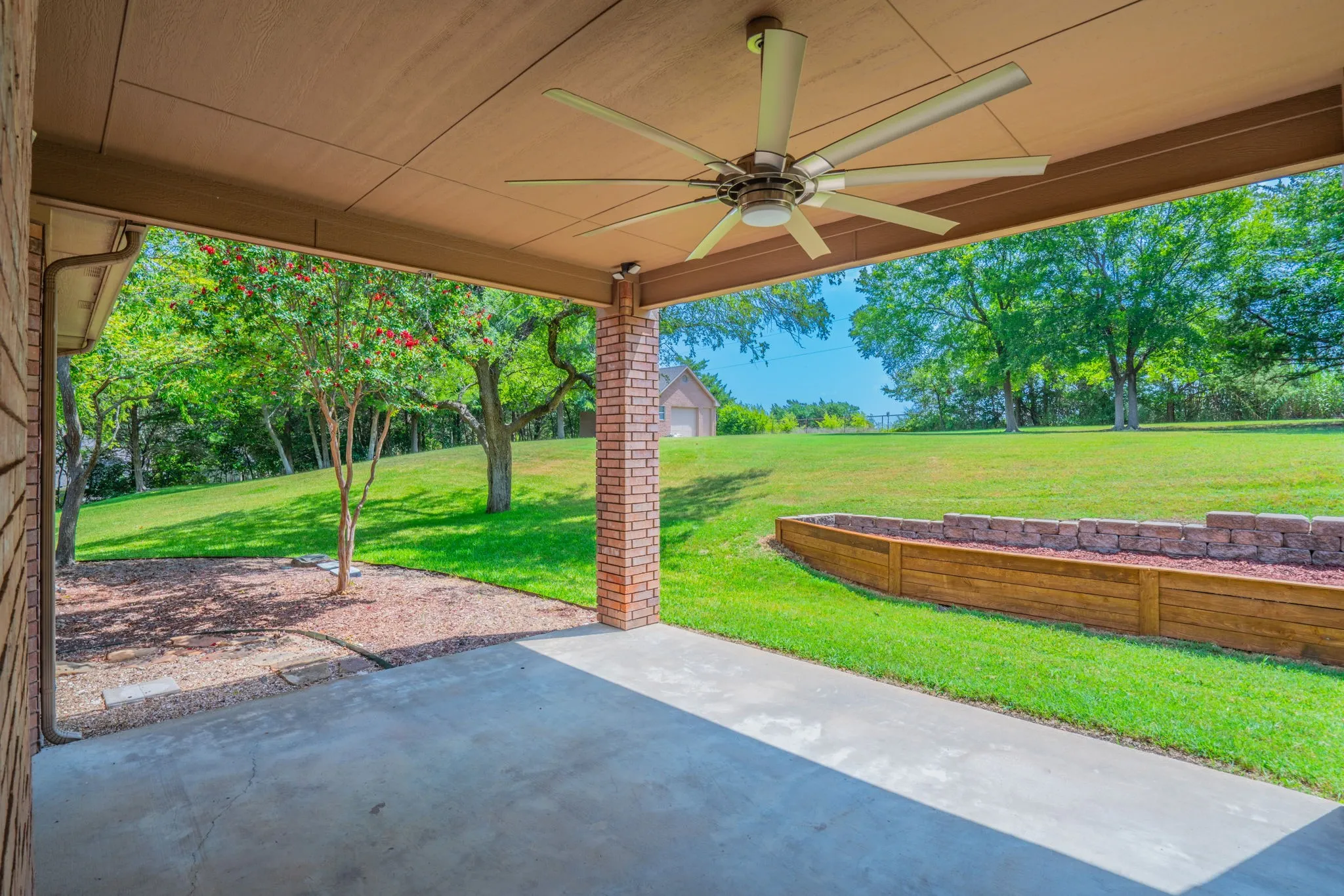 Covered outdoor patio facing the back yard with mature trees. The workshop is towards the back.