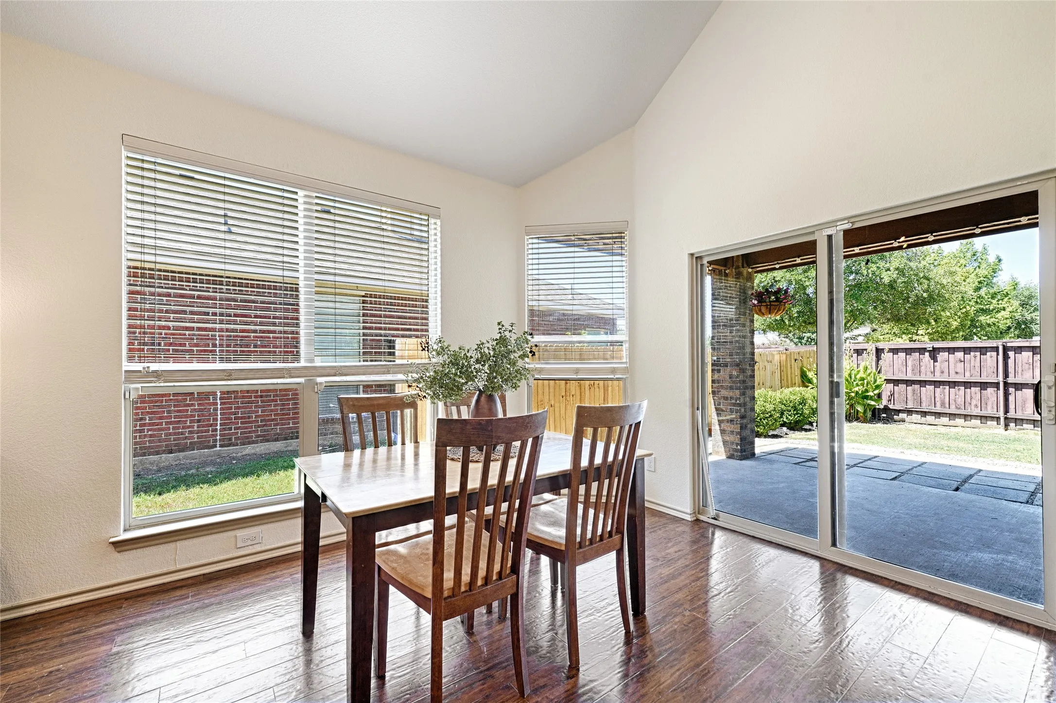 Dining area featuring wood-finish flooring, vaulted ceilings, and large windows with blinds