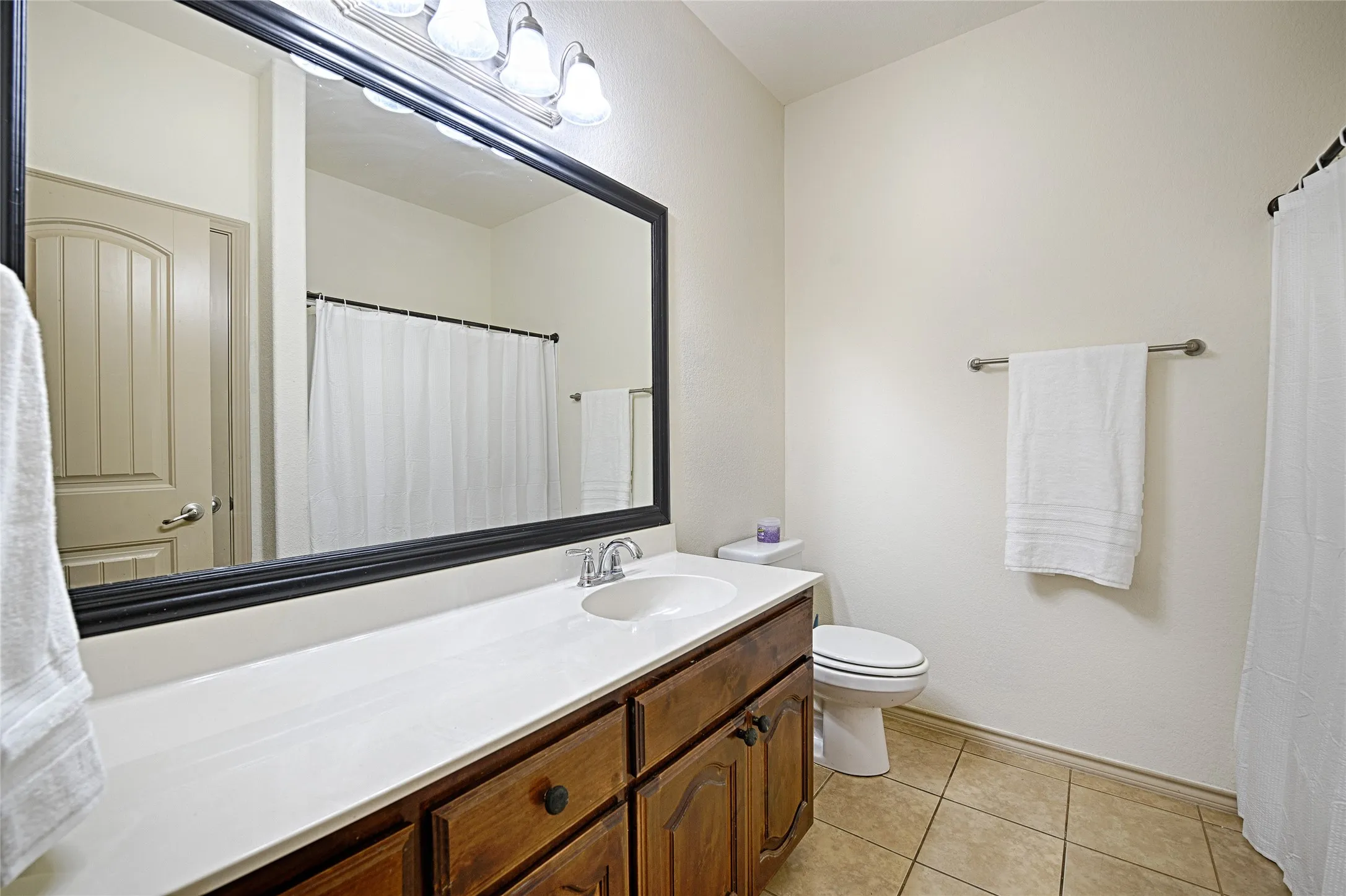 Bathroom featuring a broad vanity with wood cabinetry, a white countertop, and an integrated sink