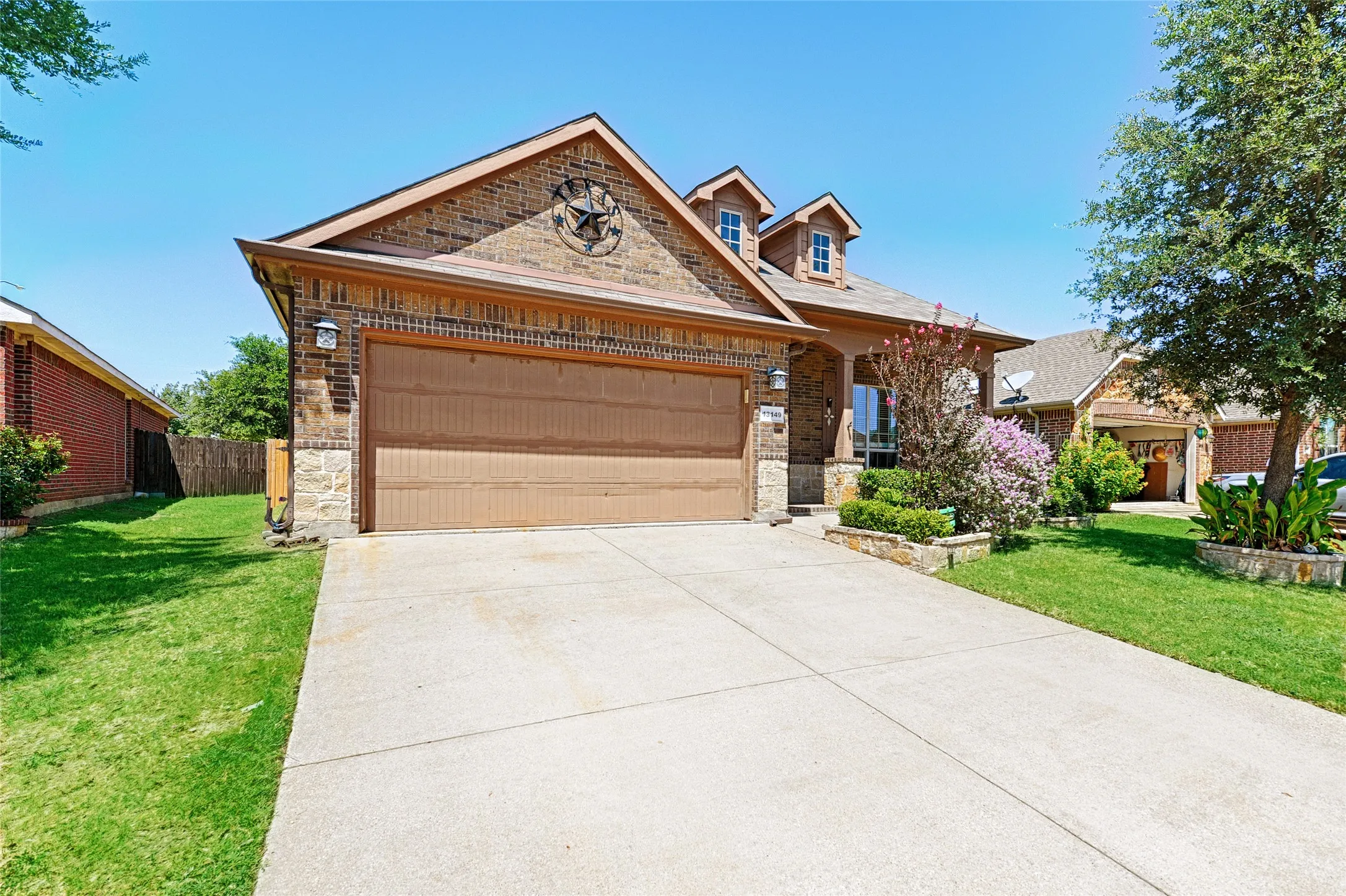 Brick exterior with a stone accent facade, featuring a two-car garage with a brown door and a concrete driveway