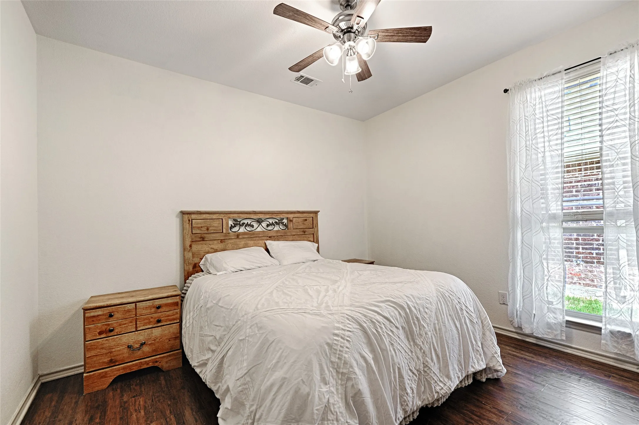 Bedroom featuring wood-finish flooring, a ceiling fan with light fixture, and a window with blinds