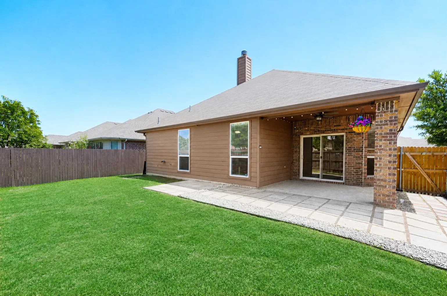 Expansive backyard featuring a large concrete patio with square paver details, a wood privacy fence, and a generous lawn