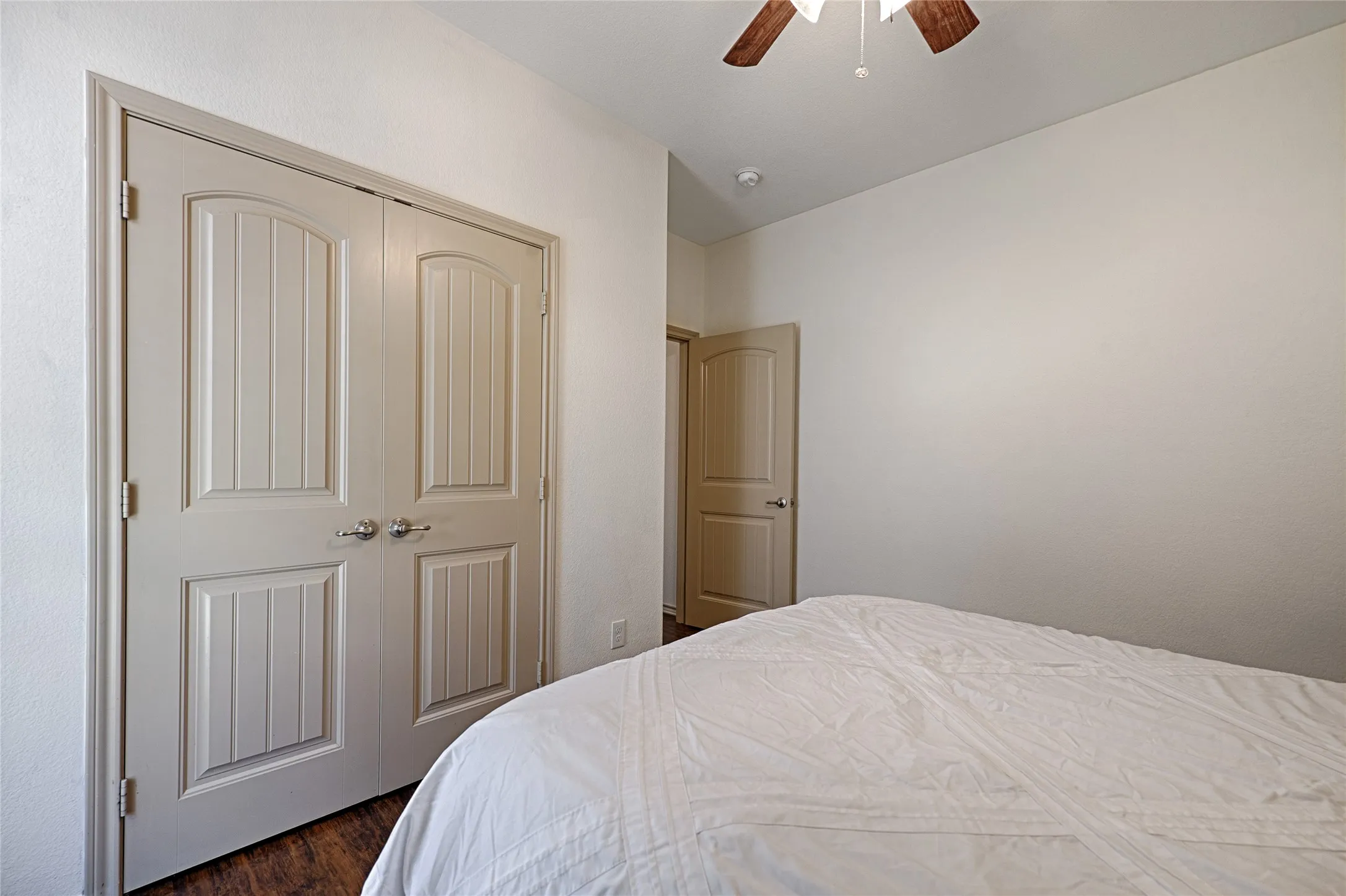 Room featuring light-toned walls, wood-finish flooring, and a ceiling fan