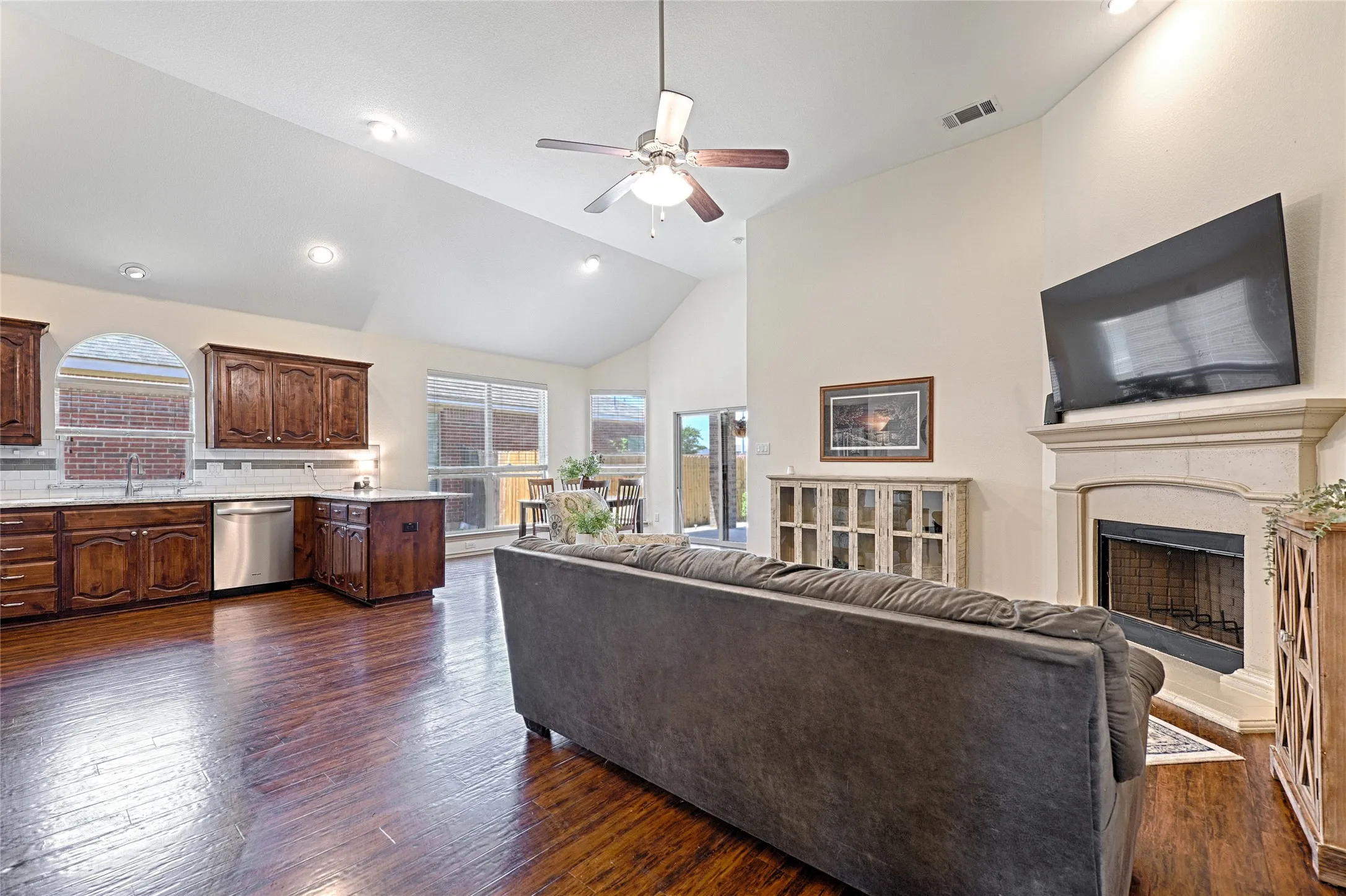 Open-concept living area featuring a vaulted ceiling with a ceiling fan, recessed lighting, and wood-finish flooring