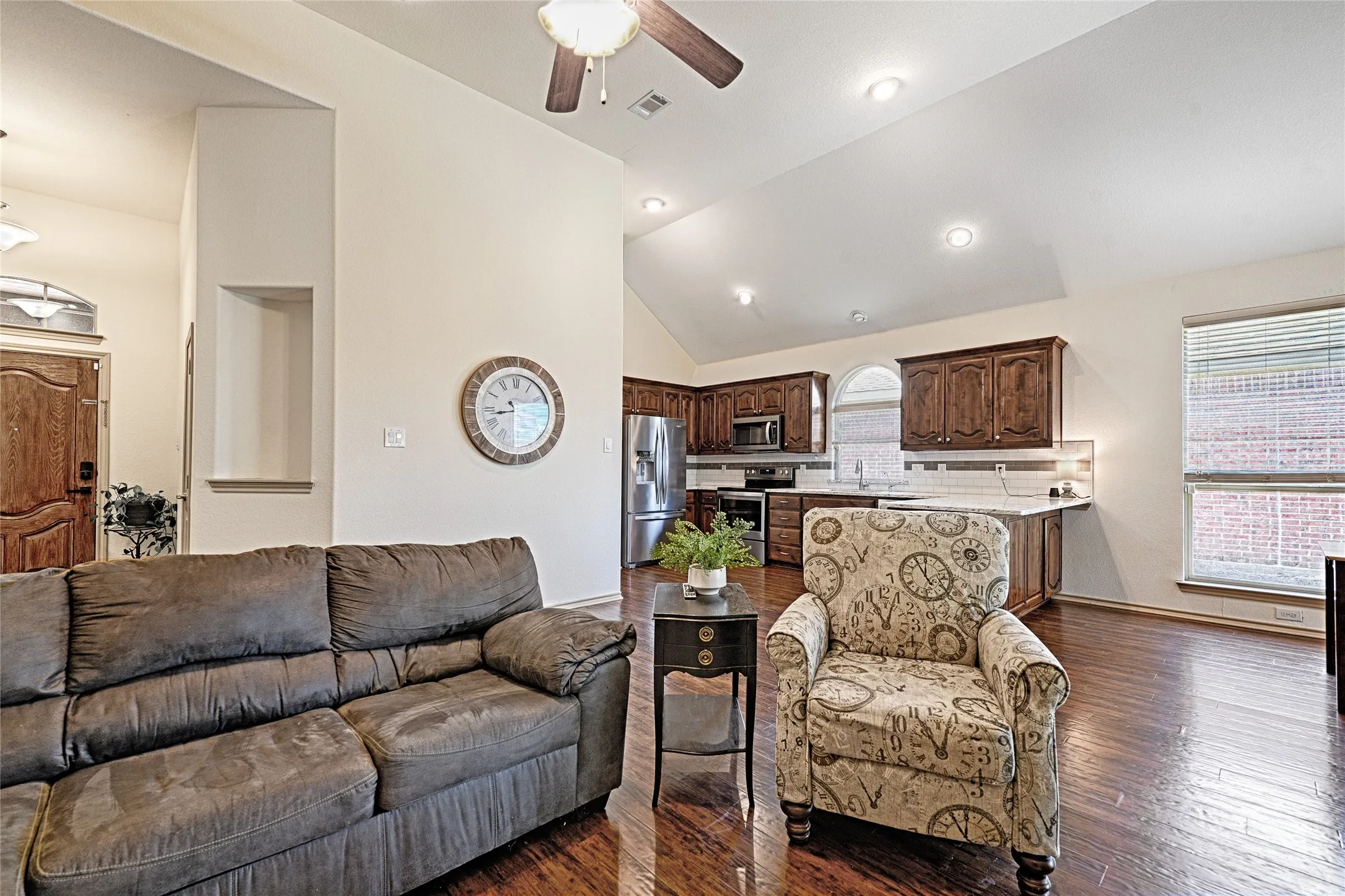 Open-concept living area featuring wood-finish flooring, vaulted ceilings, and recessed lighting