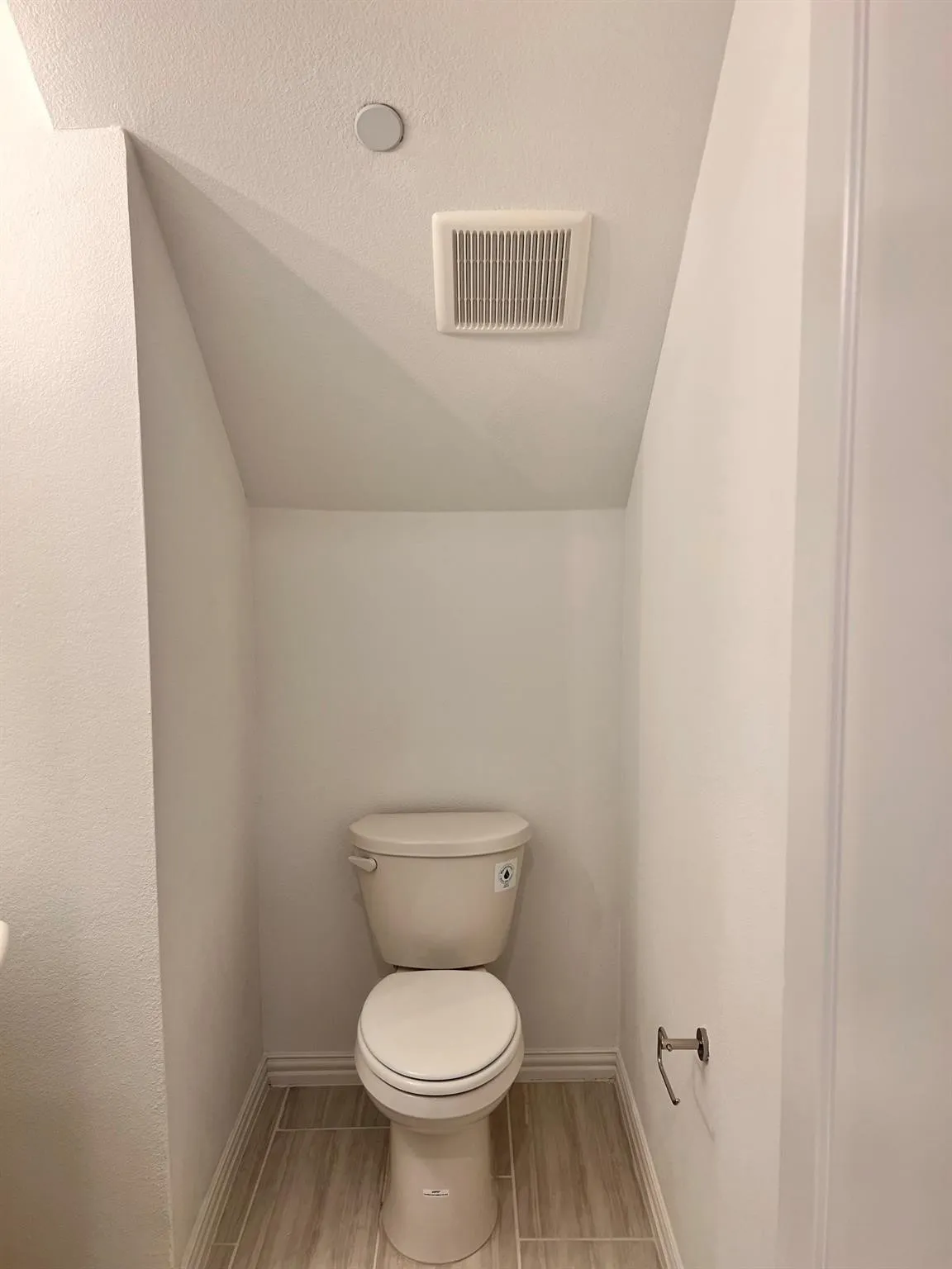Powder room featuring a single toilet, wood-look tile flooring, and a ceiling-mounted exhaust fan