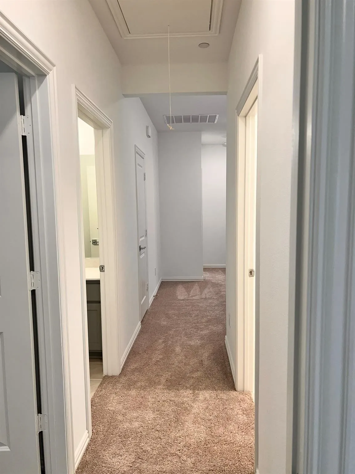 Carpeted hallway featuring white walls and baseboards