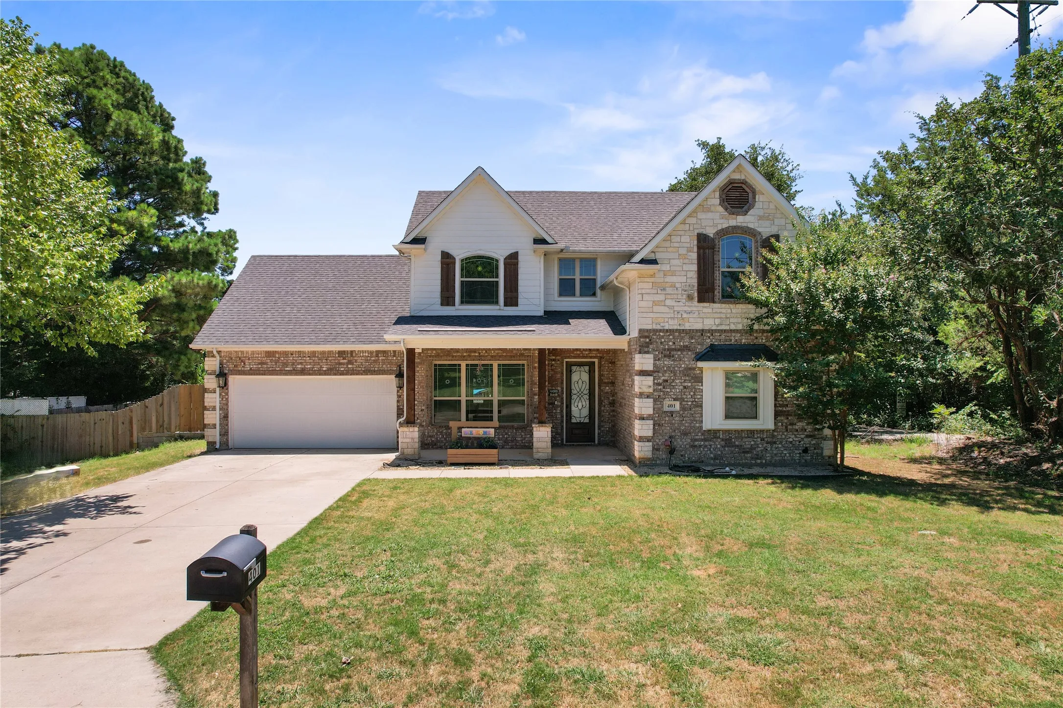 Two-story residence featuring a brick and stone facade, a gabled roofline, an attached two-car garage on a half acre lot wooded lot!