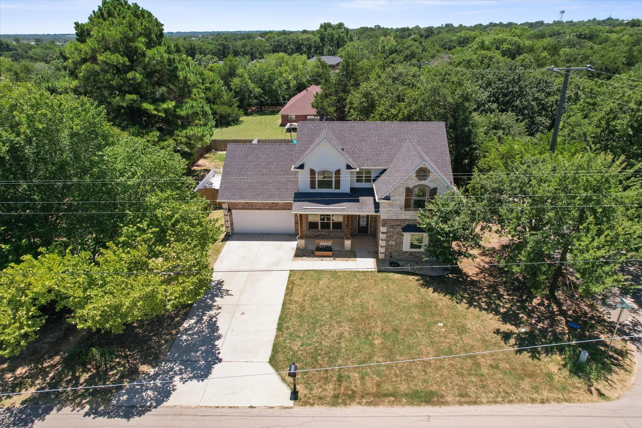Two-story residence featuring a combination of brick and stone, a covered front porch, an attached garage and a concrete driveway