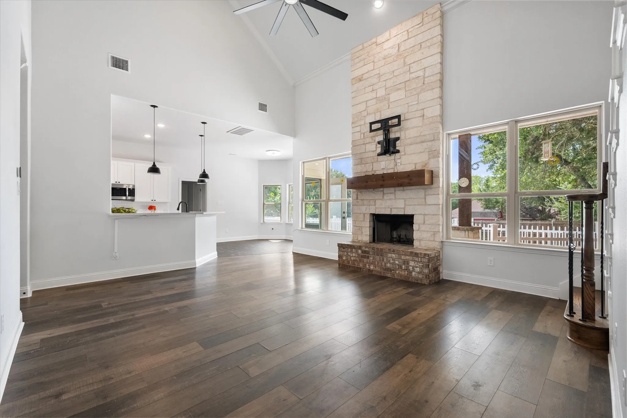 Open-concept living space featuring soaring vaulted ceilings with ceiling fan, dark wood-finish flooring throughout, and nice views of the backyard