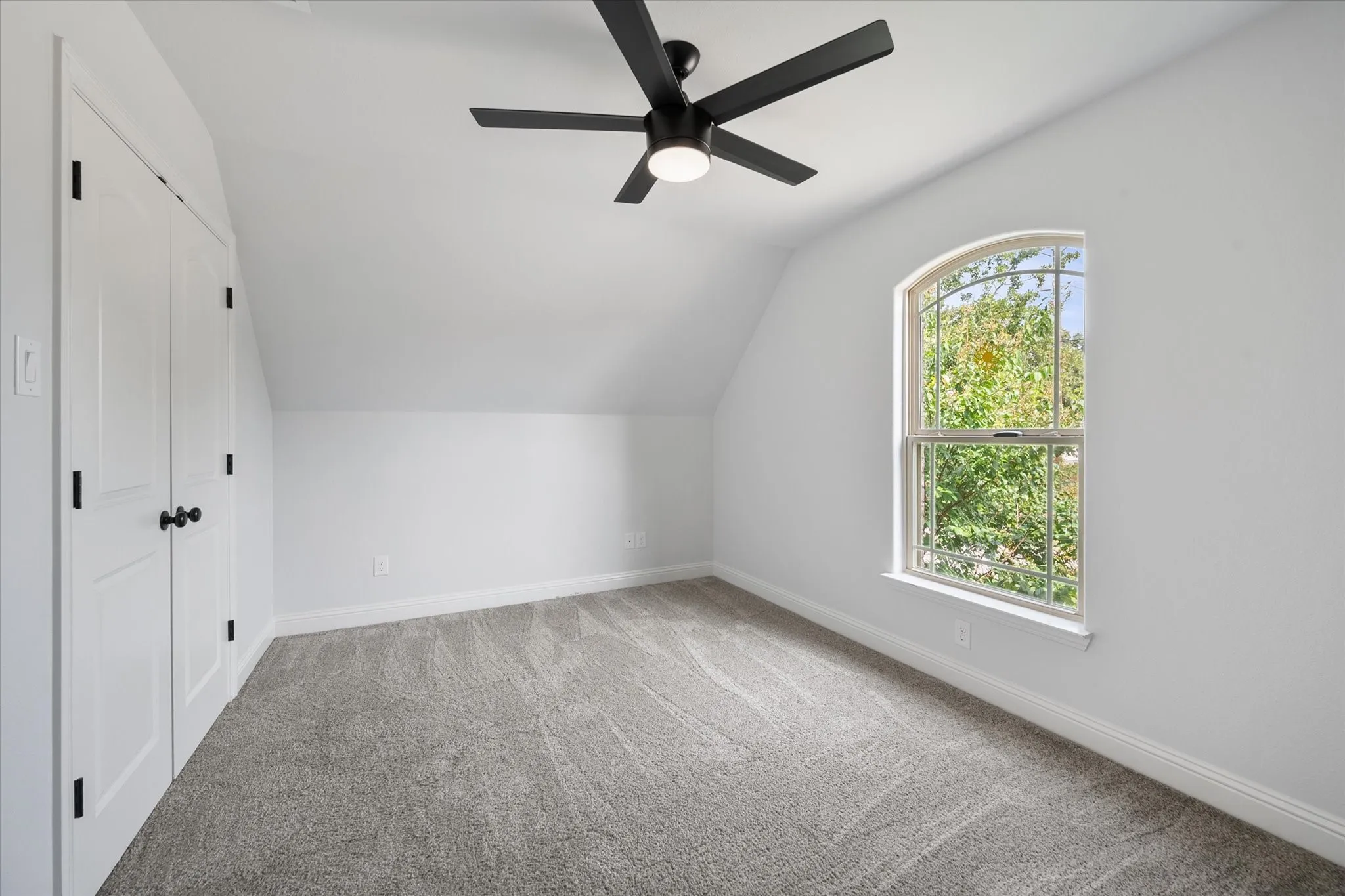 Bedroom 2 has an arched window, soft carpet flooring and a contemporary ceiling fan