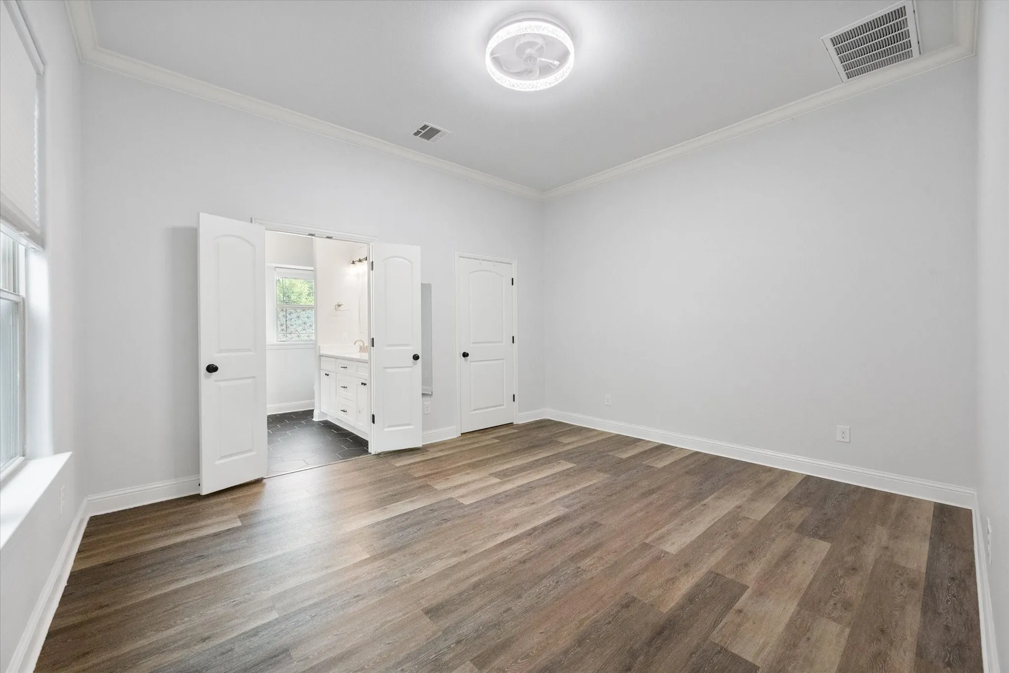 Primary Suite features wood-look flooring, ceiling fan, nice sized walk-in closet and an ensuite bathroom