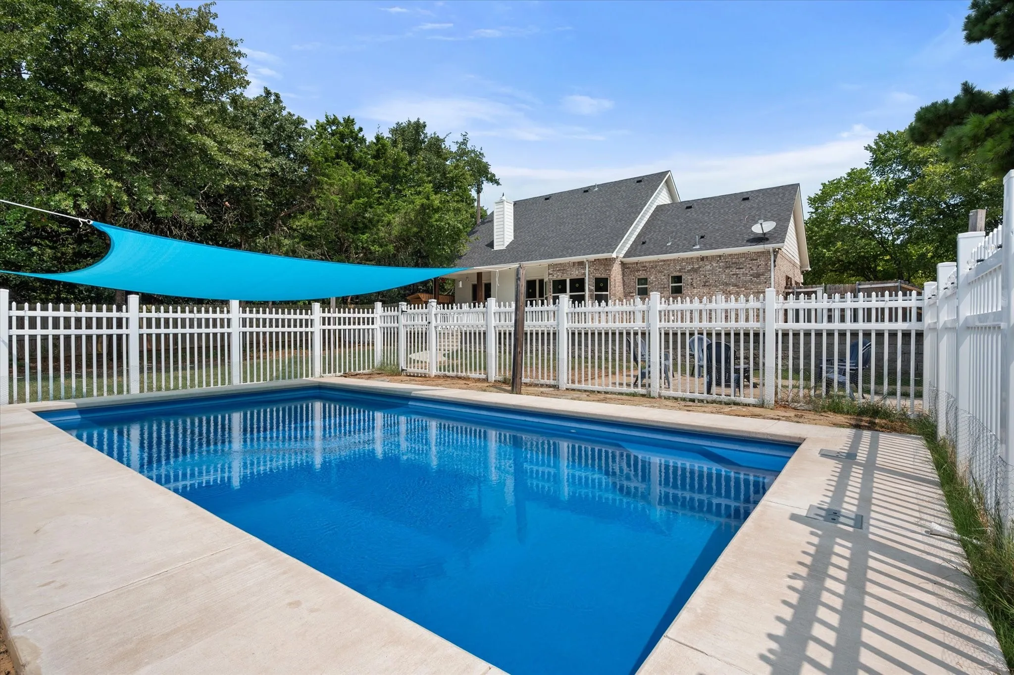 Another view of the in-ground swimming pool with concrete surround looking back towards the home