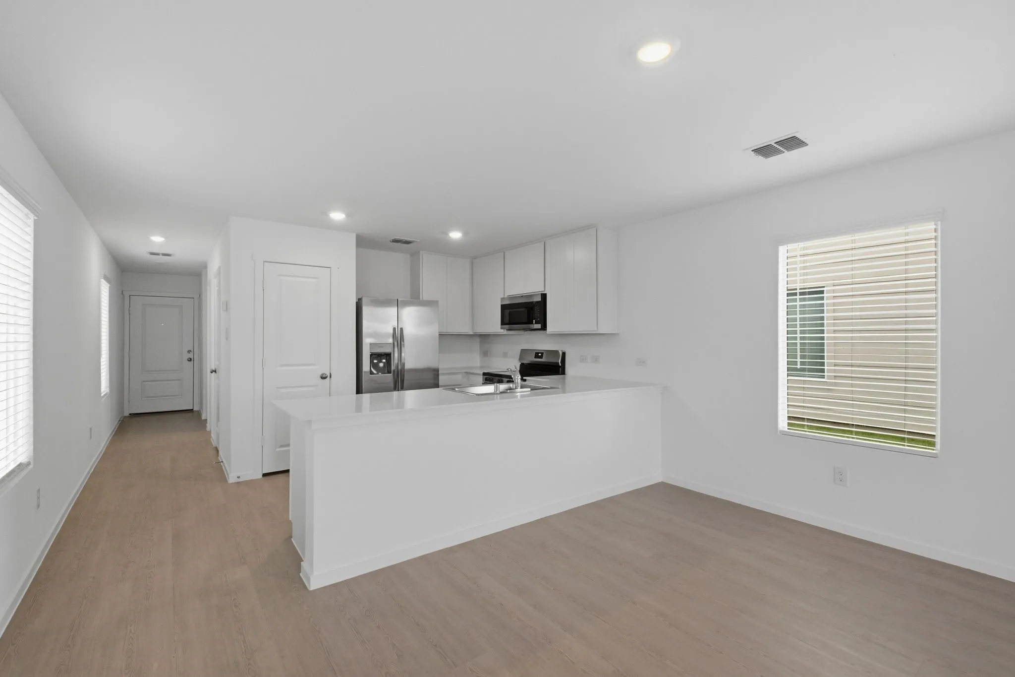 Open-concept living space featuring wood-finish flooring, recessed lighting, and a kitchen island with a light-toned countertop