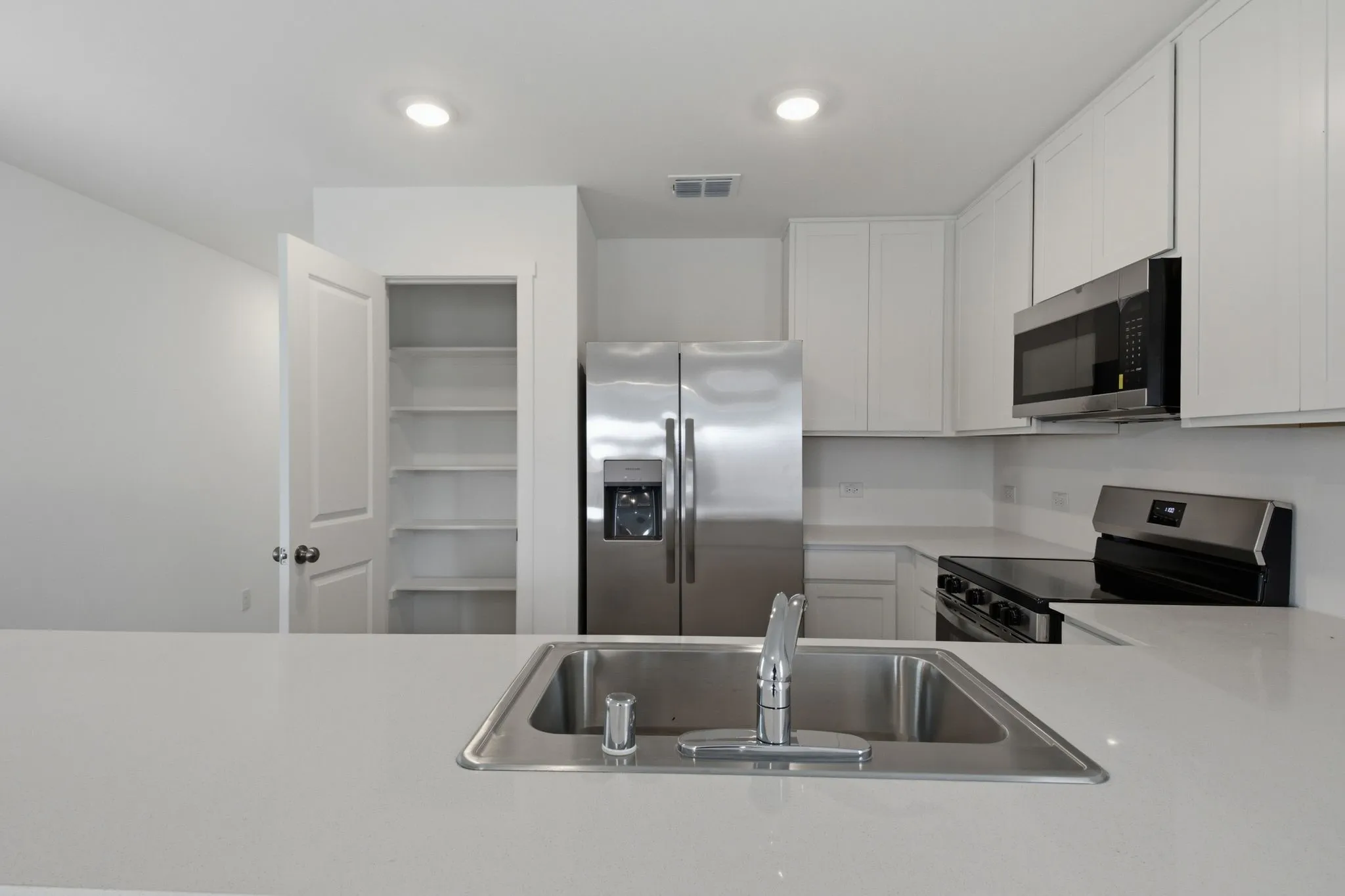 Modern kitchen featuring an undermount stainless steel sink, a stainless steel side-by-side refrigerator, and a stainless steel oven range with an overhead microwave