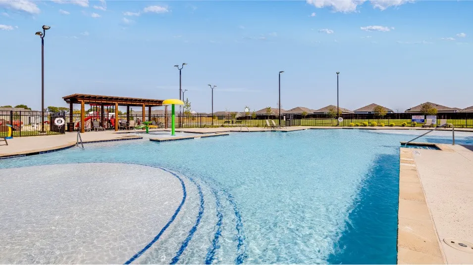 Expansive community swimming pool featuring a tanning ledge with stepped entry, an in-pool play structure, and a covered pergola with seating