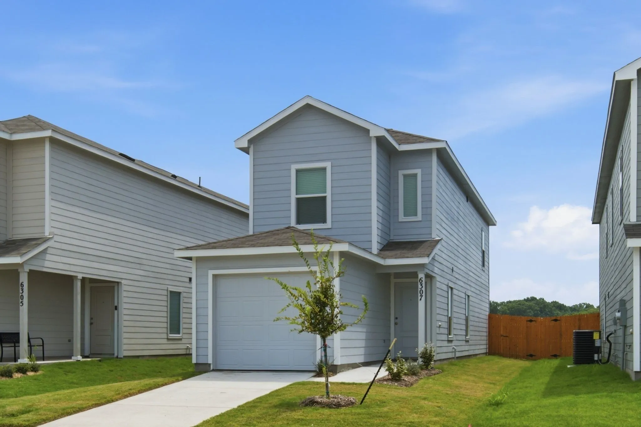Two-story property featuring light blue siding, an attached single-car garage, and a concrete driveway