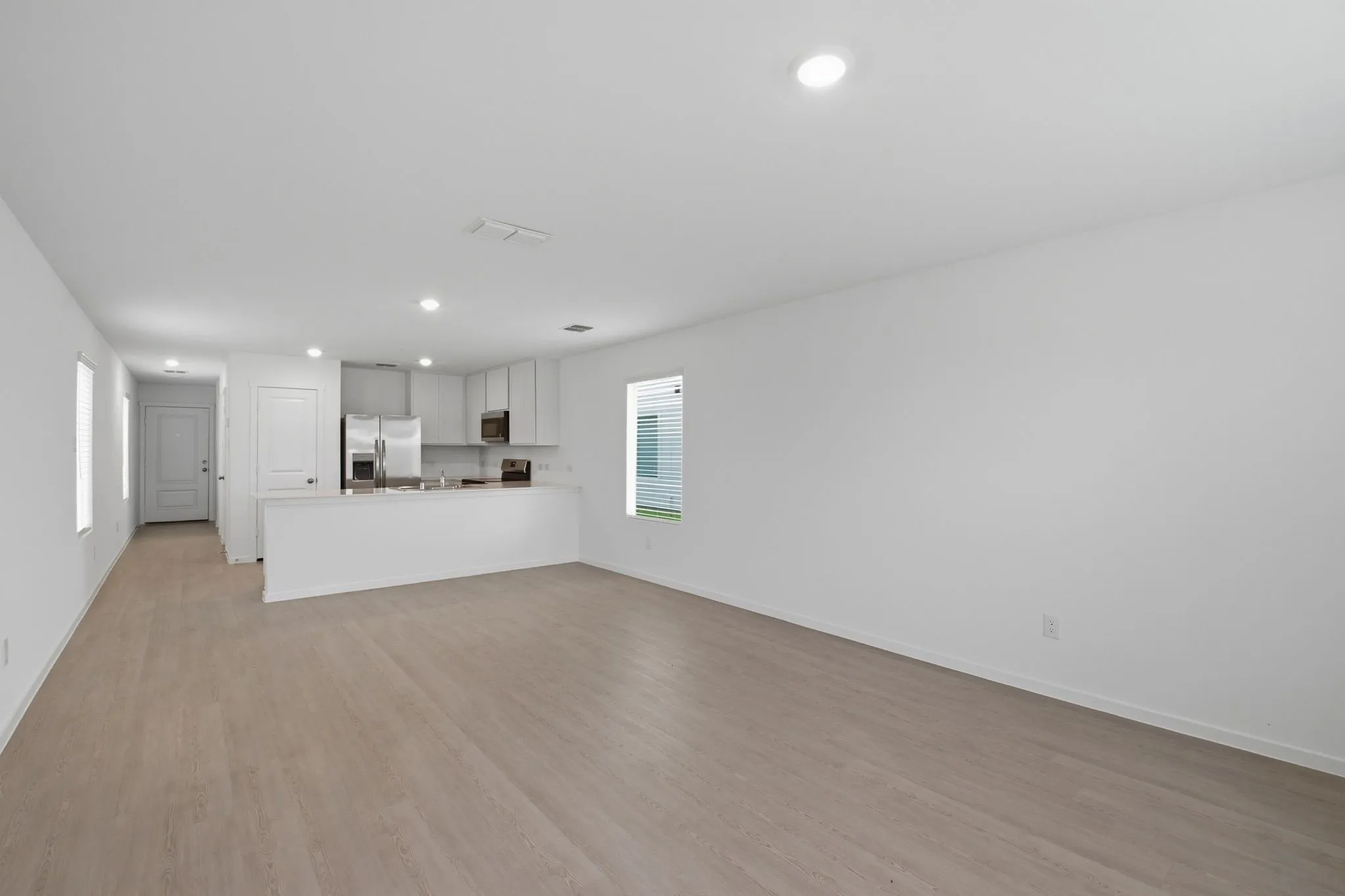 Open-concept living area featuring wood-finish flooring, recessed lighting, and a neutral color palette