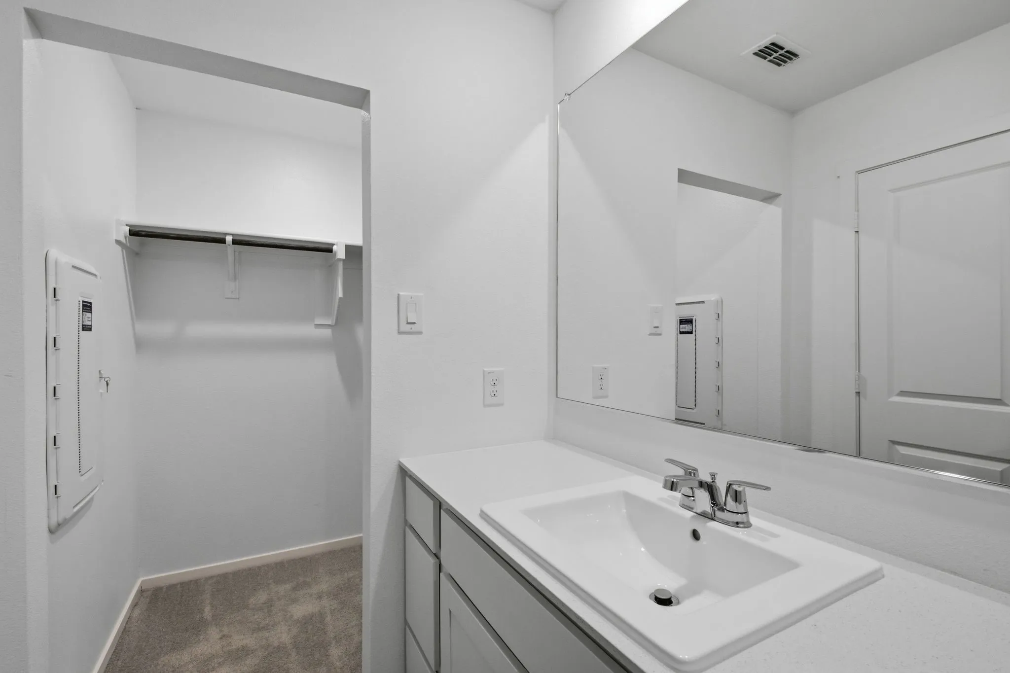 Bathroom vanity featuring an integrated rectangular sink, chrome faucet, and expansive wall-mounted mirror