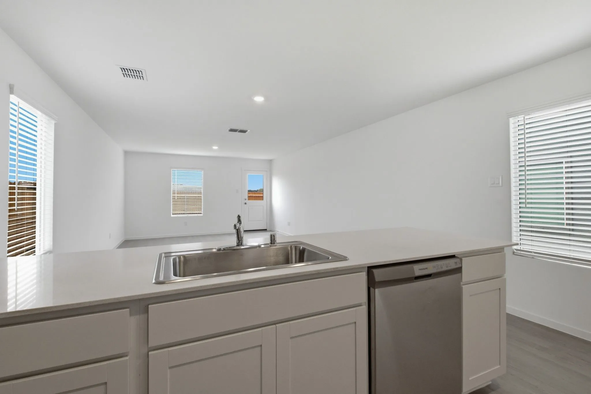 Kitchen island featuring a stainless steel sink, a stainless steel dishwasher, and a light-toned countertop