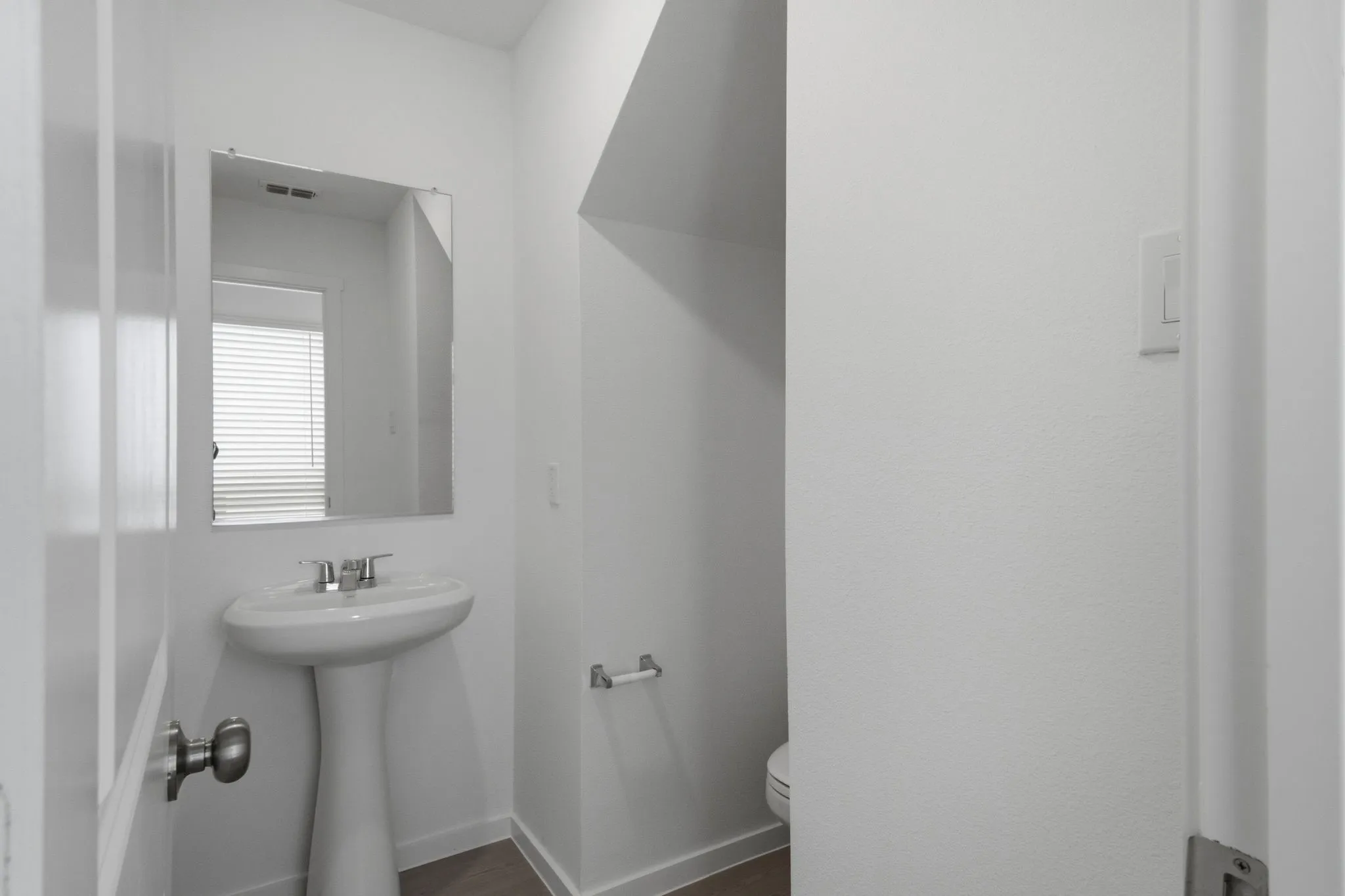 Pedestal sink with chrome faucet and rectangular mirror in a bright powder room