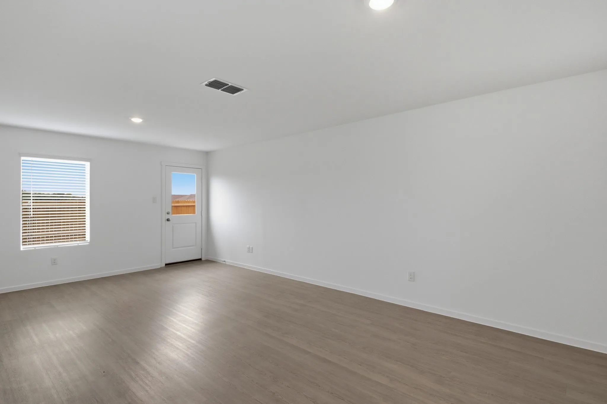 Spacious room with wood-finish flooring, white walls, and recessed lighting