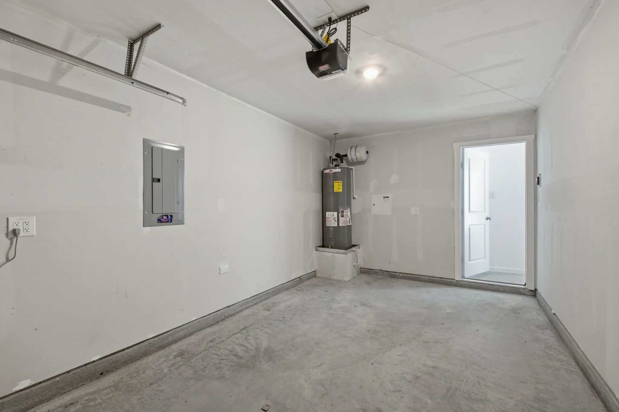 Attached garage space featuring a concrete floor, painted walls, and an overhead garage door track system