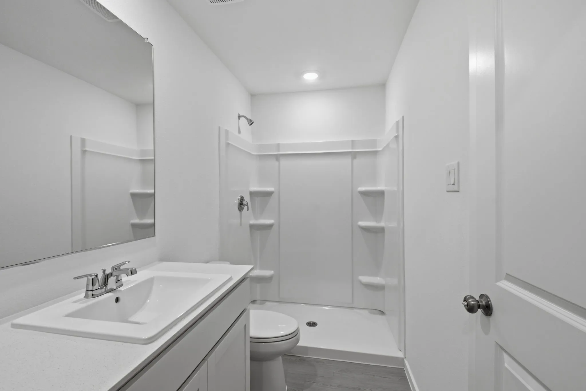 Bathroom featuring a single vanity with a white countertop and integrated sink, chrome faucet, and a large wall-mounted mirror