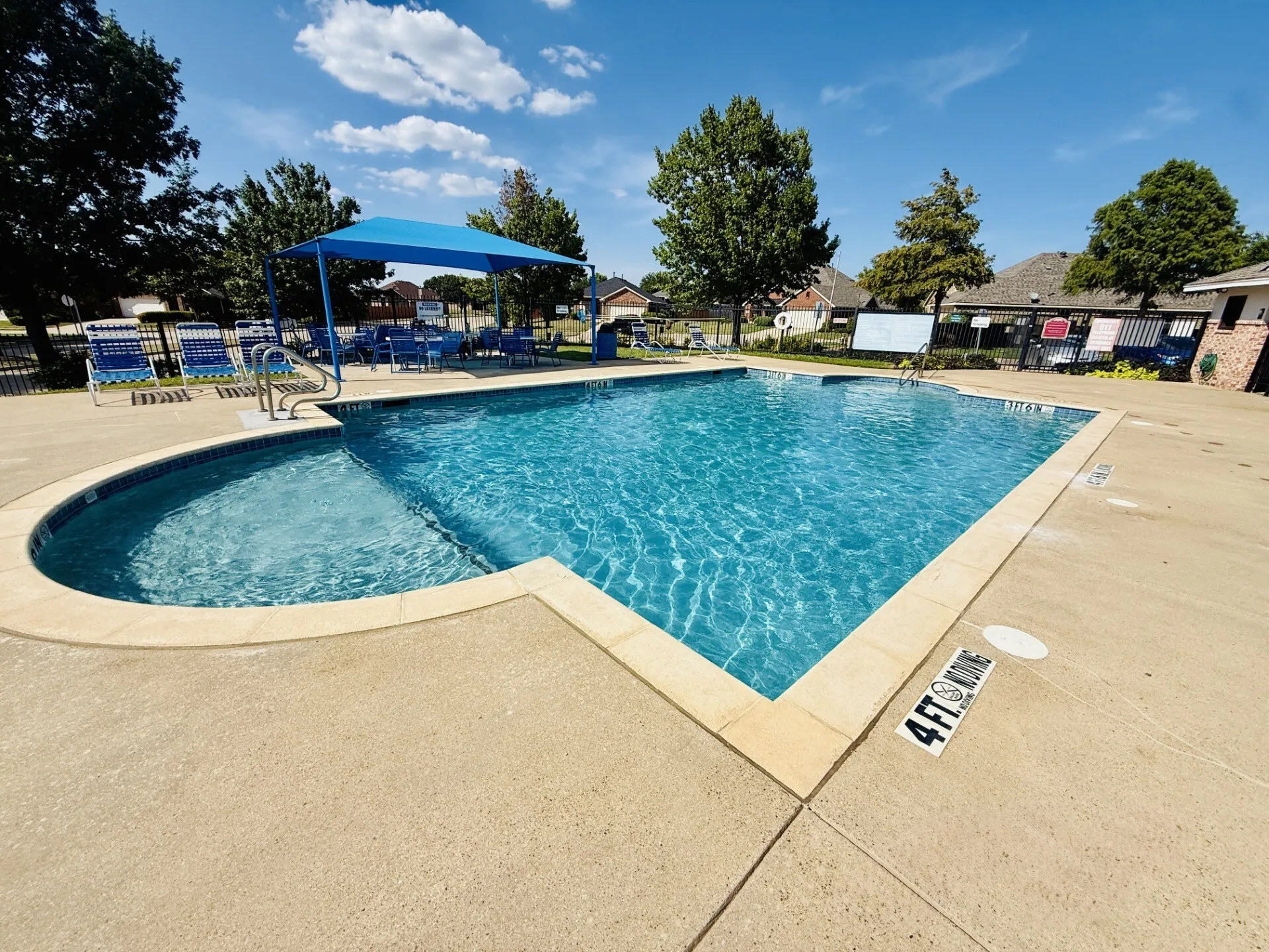 Community swimming pool featuring a concrete deck and blue tile coping