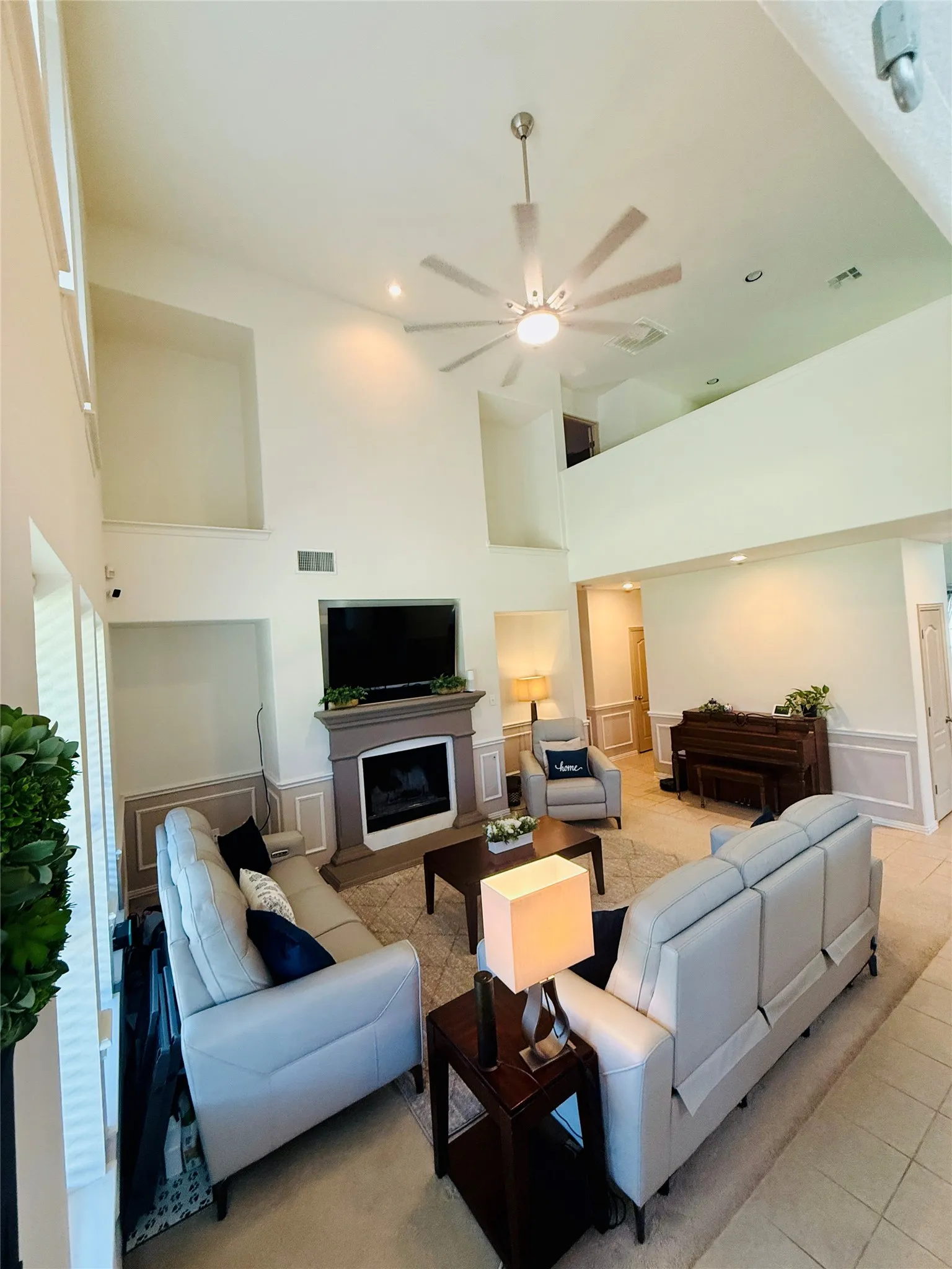 Vaulted ceiling living room featuring a fireplace with a decorative mantel, a ceiling fan, recessed lighting, and an upper-level overlook