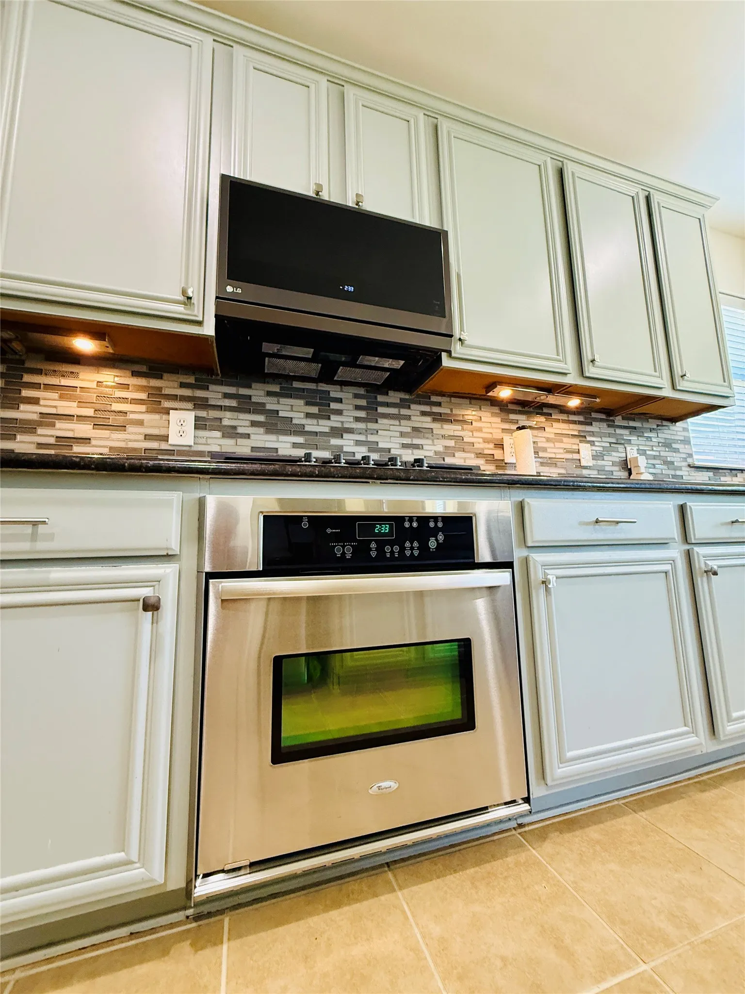 Built-in stainless steel oven with a framed window, complemented by a black cooktop and an over-the-range microwave