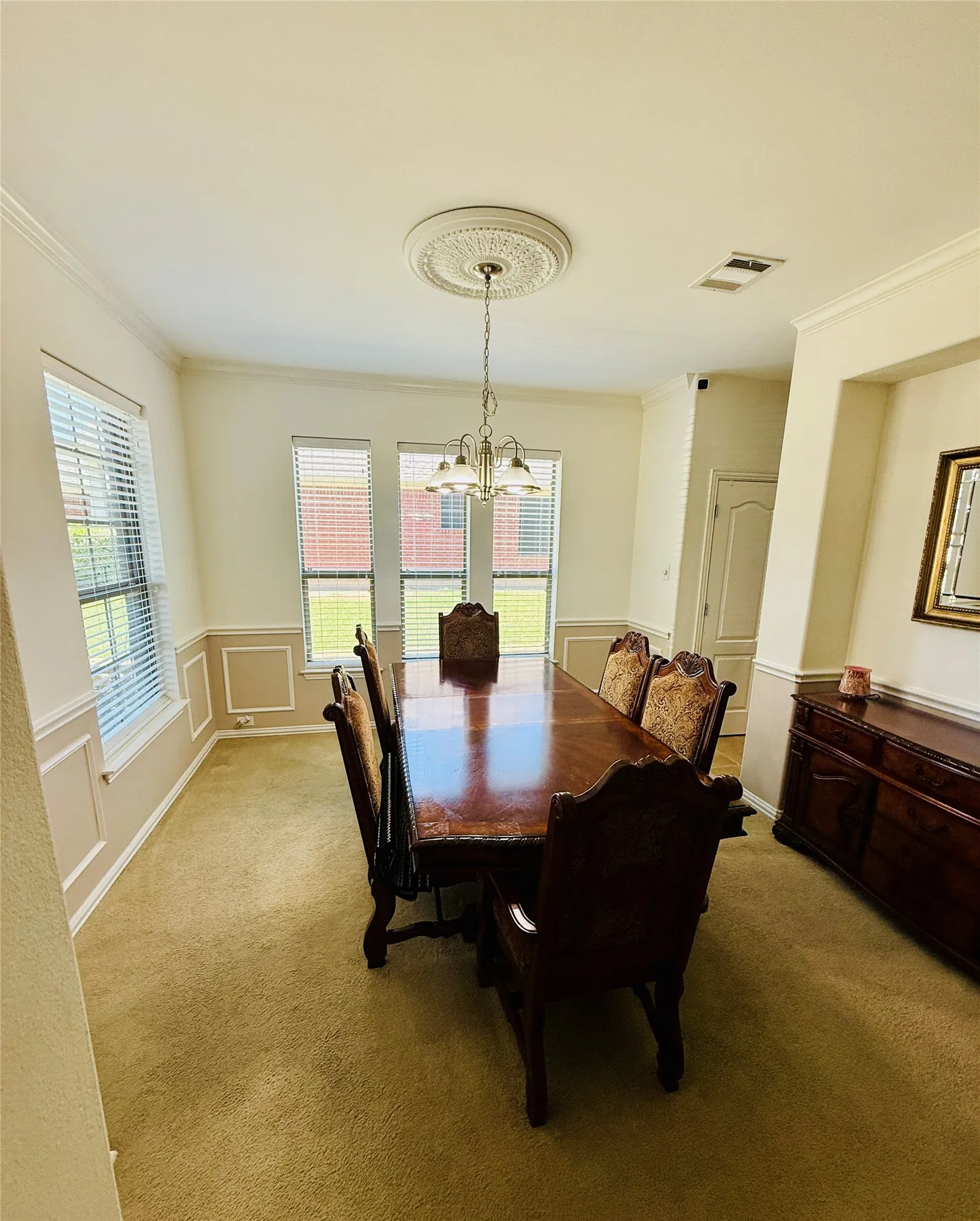 Dining area featuring three windows, crown molding, and wainscoting