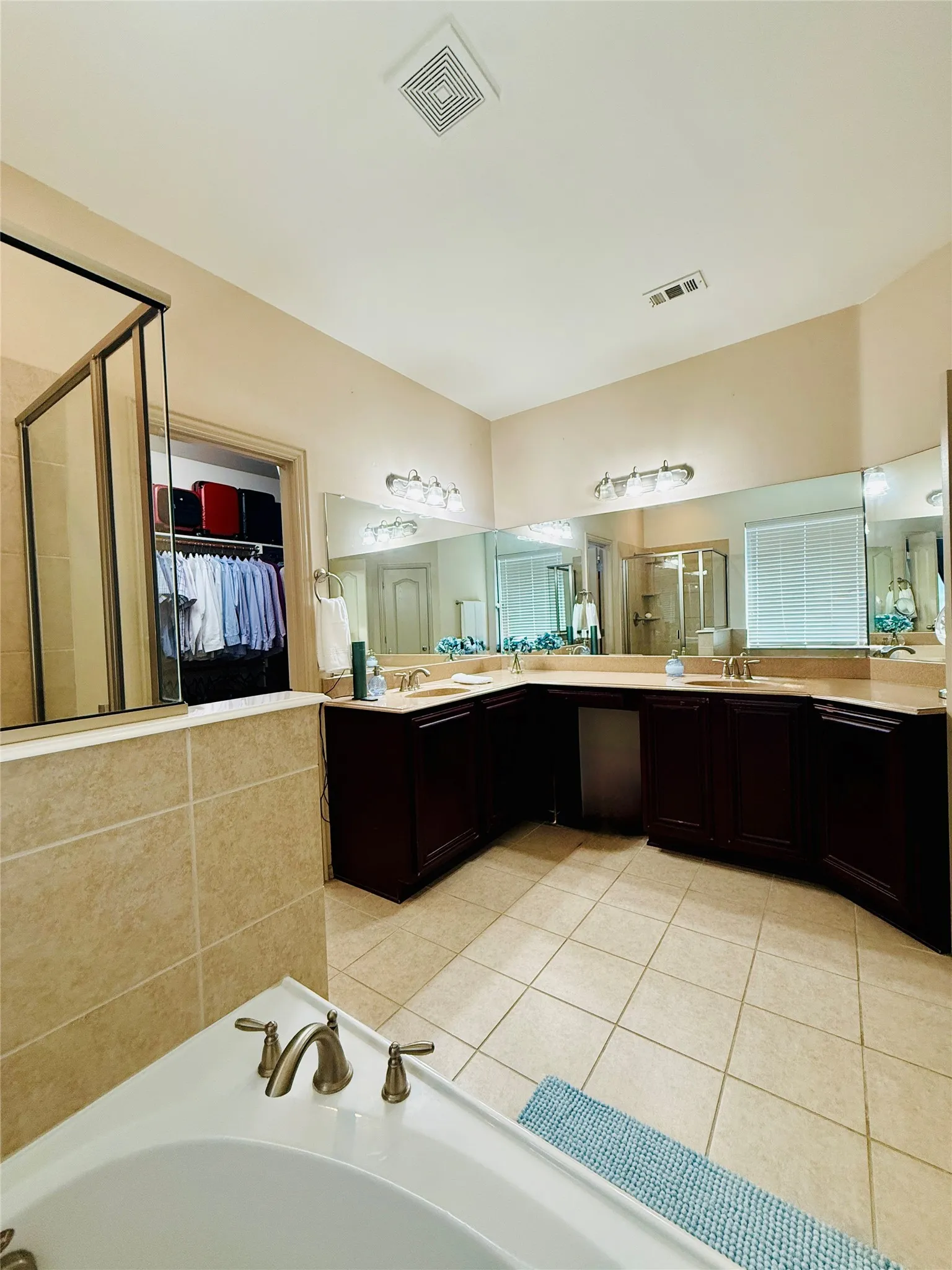 Spacious bathroom featuring a corner soaking tub with brushed nickel fixtures, a large shower enclosure, and extensive dark wood cabinetry