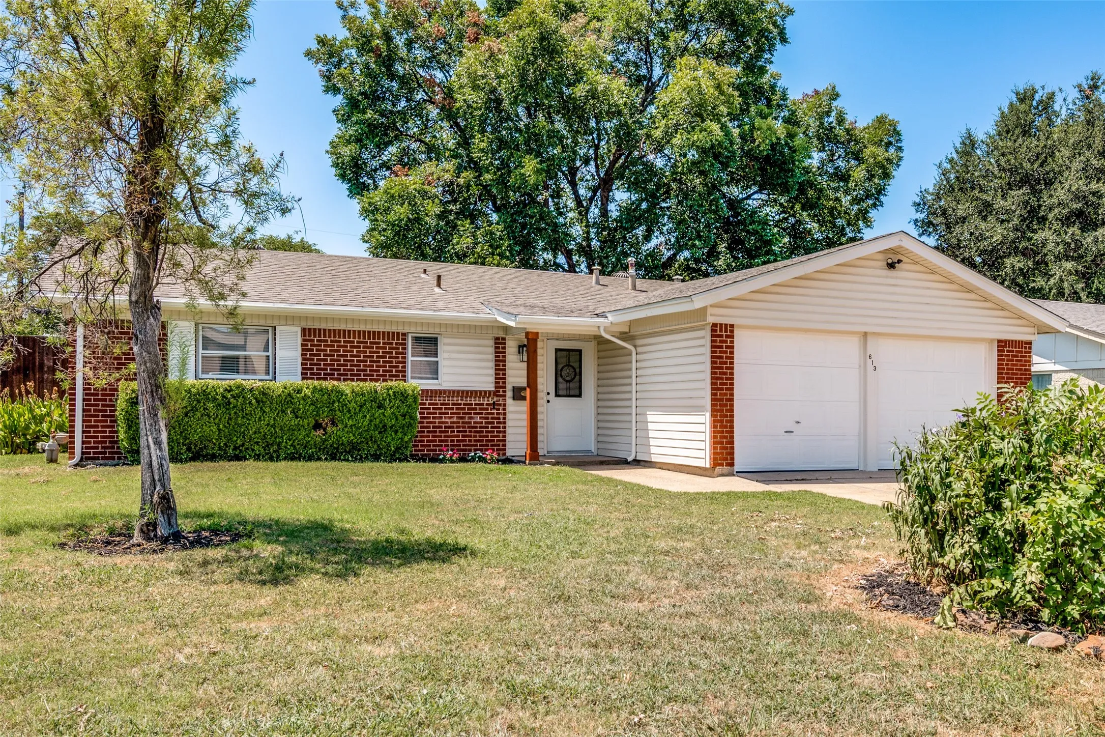 Ranch-style exterior featuring brick and horizontal siding, a covered entry, and an attached two-car garage