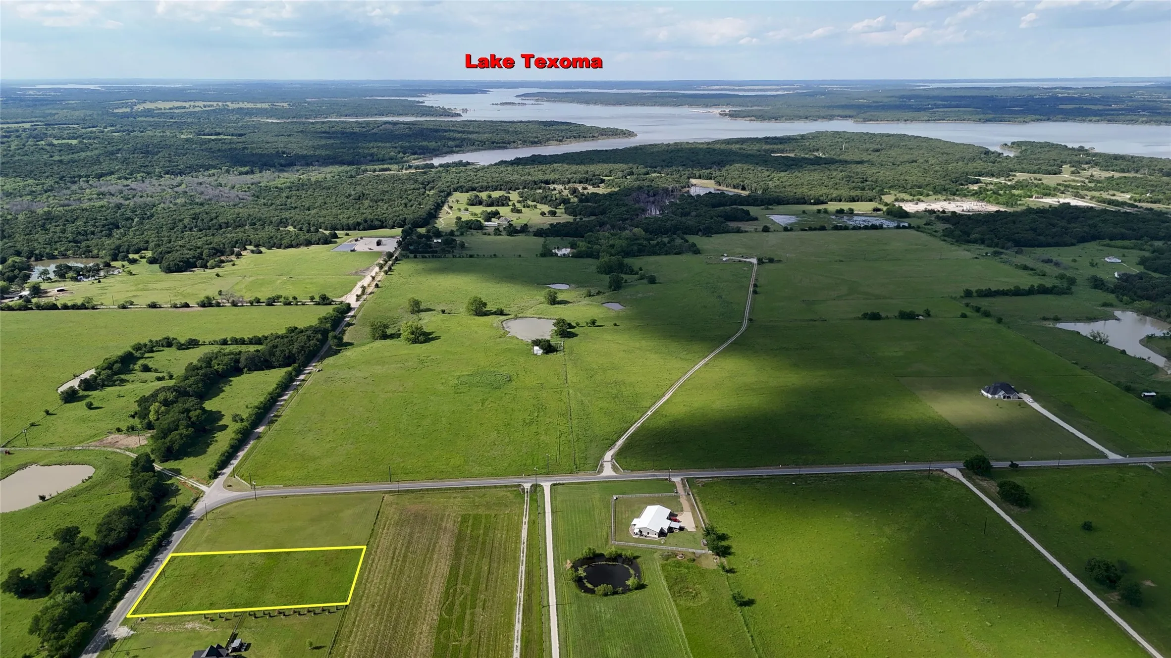Expansive green landscape featuring a highlighted rectangular parcel, surrounded by additional green fields and wooded areas