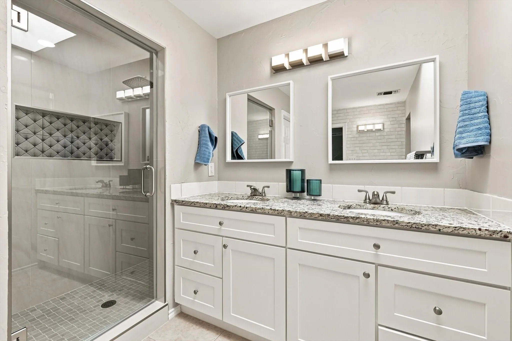 Double vanity with granite countertops, undermount sinks, and white shaker-style cabinetry