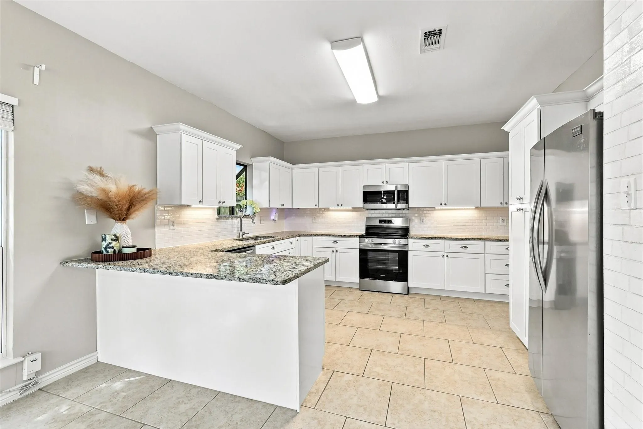 Kitchen featuring white cabinetry, granite countertops, tile flooring, and stainless steel appliances