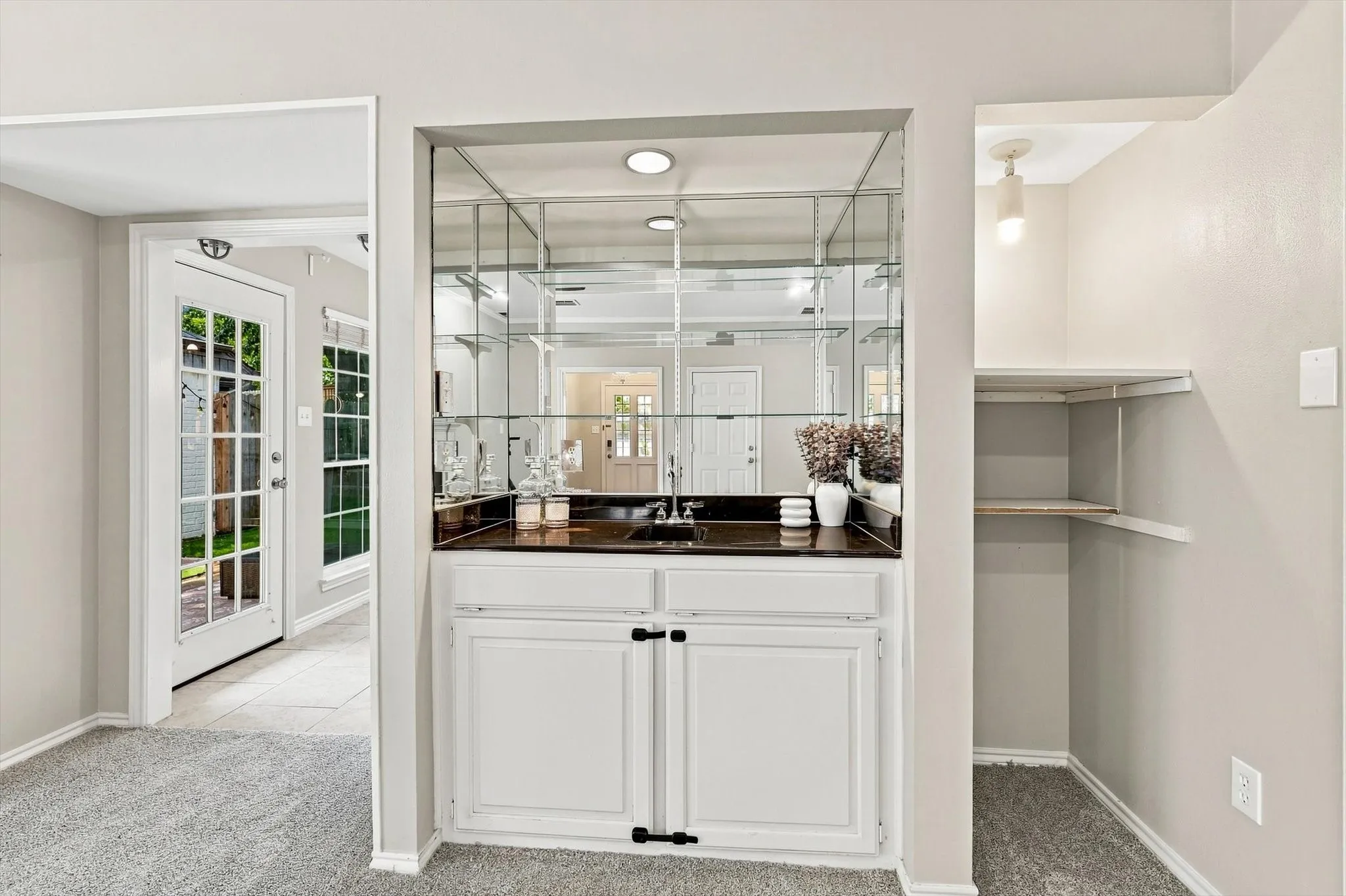 Built-in wet bar with a dark countertop and mirrored backing