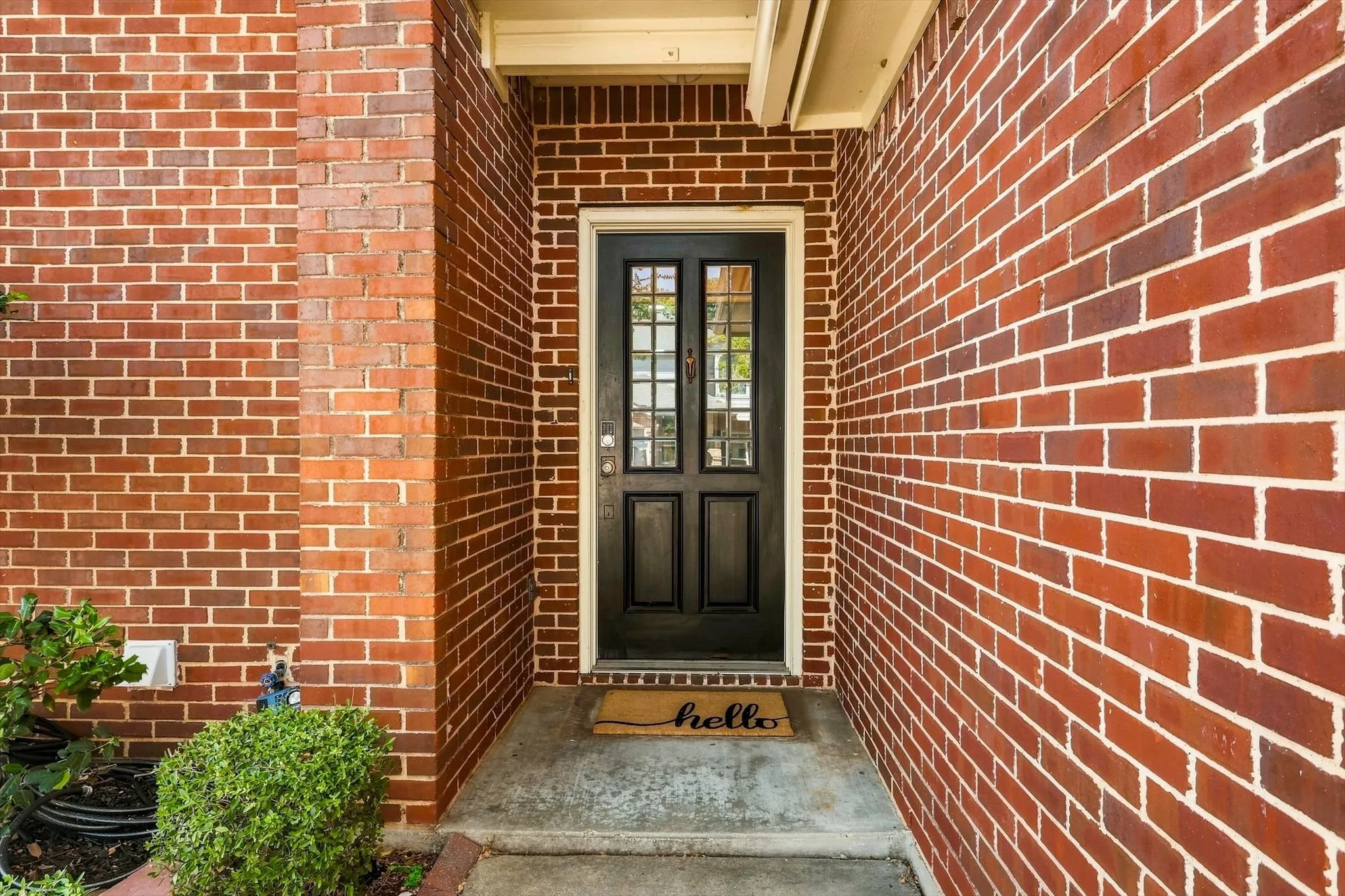 Brick exterior with a dark wood-finish front door featuring glass paneling