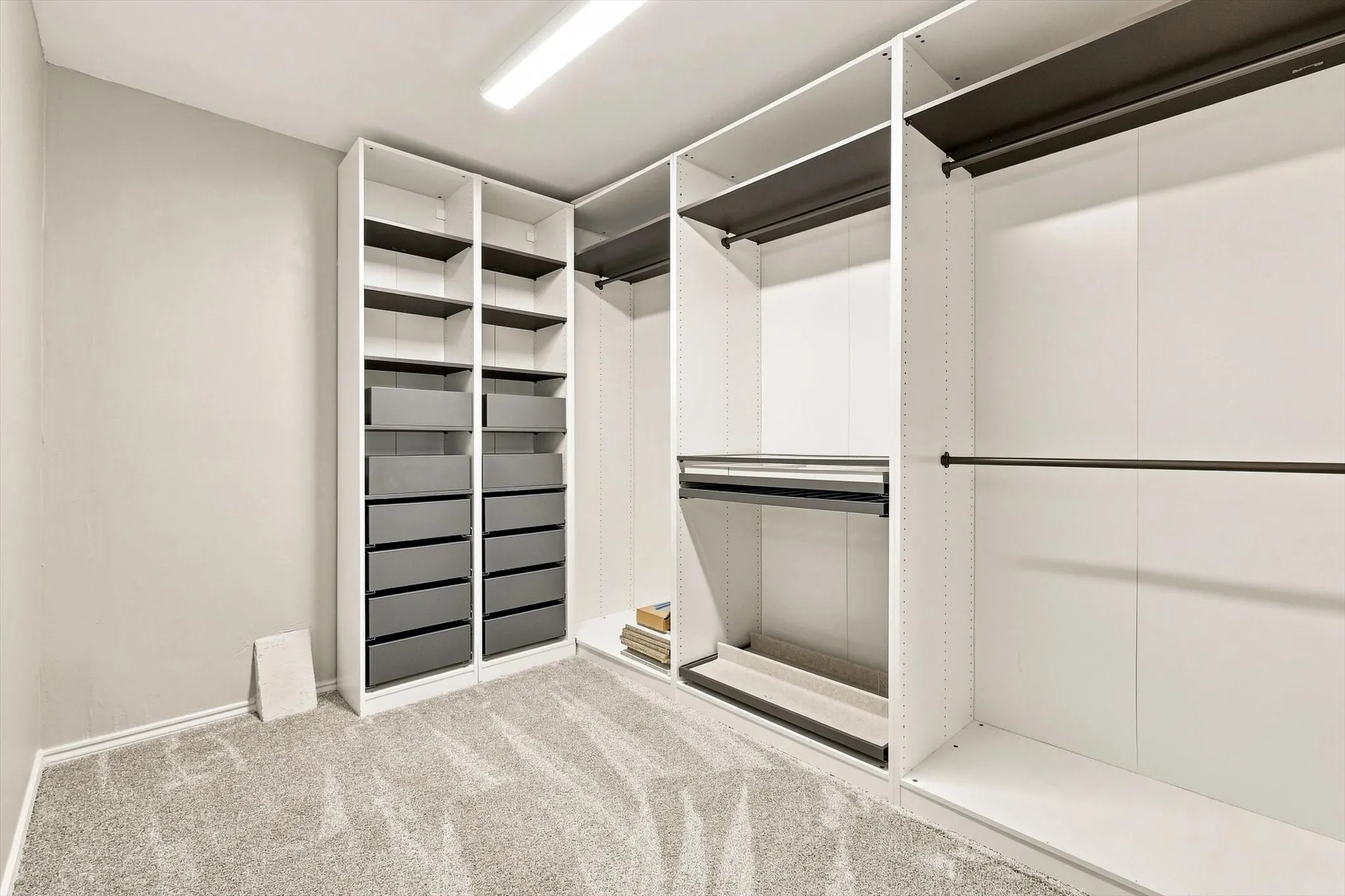 Custom closet system with integrated shelving and drawers, multiple hanging rods, and recessed lighting