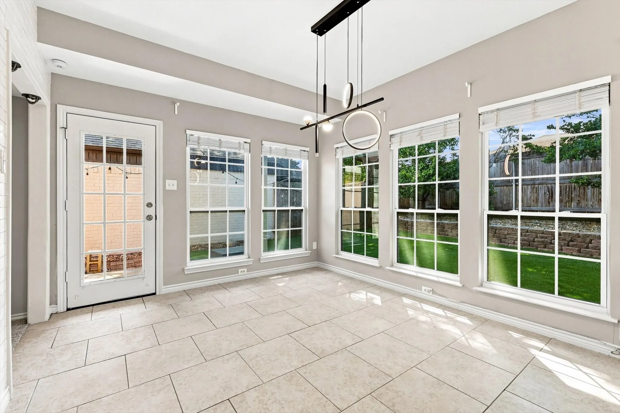 Recessed ceiling, transom window, contemporary linear light fixture, multiple large windows, and light-toned tile flooring