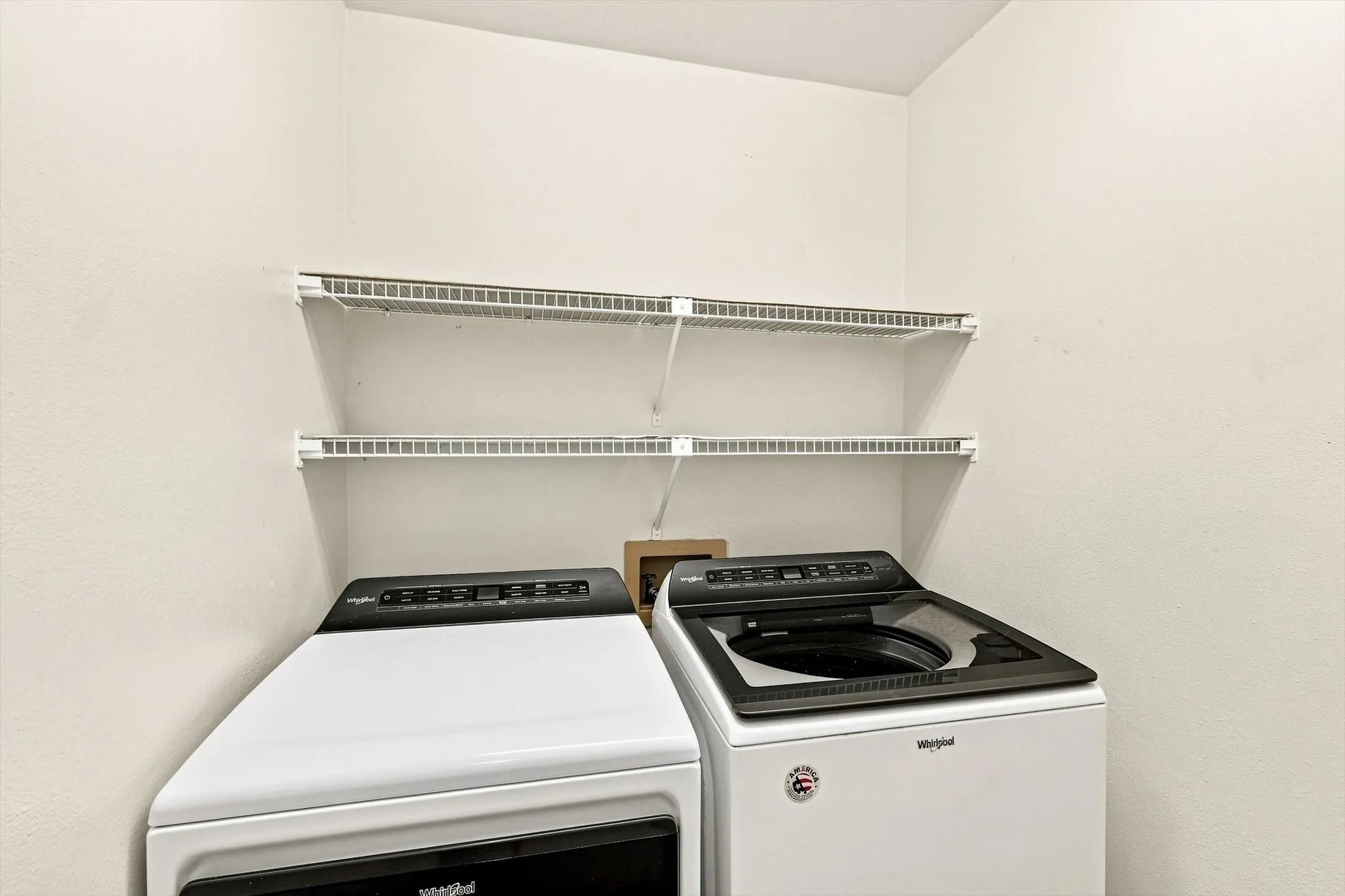Two white wire shelves mounted on a light-colored wall