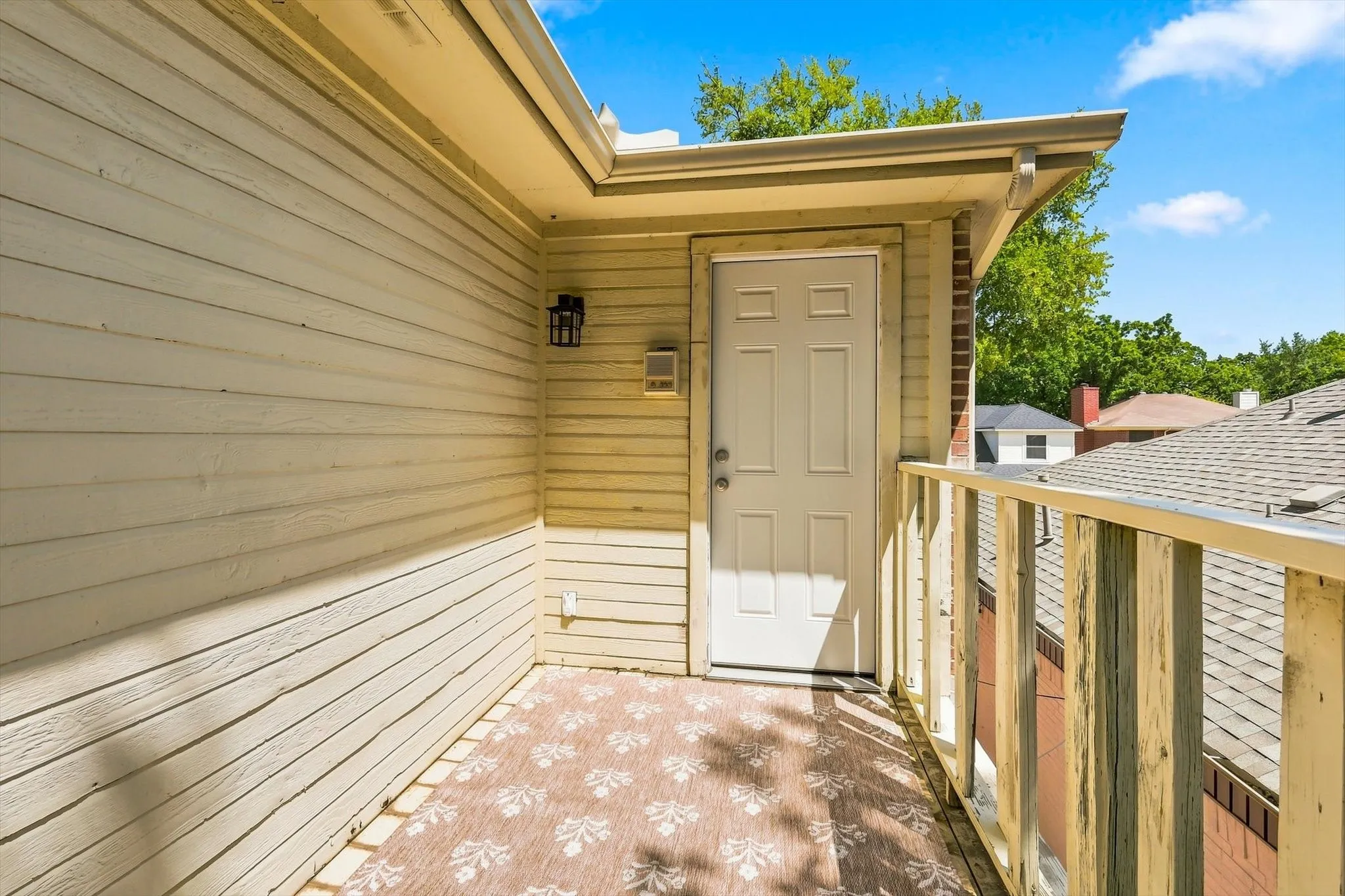 Private balcony featuring horizontal siding, a paneled exterior door, and a built-in wall light fixture