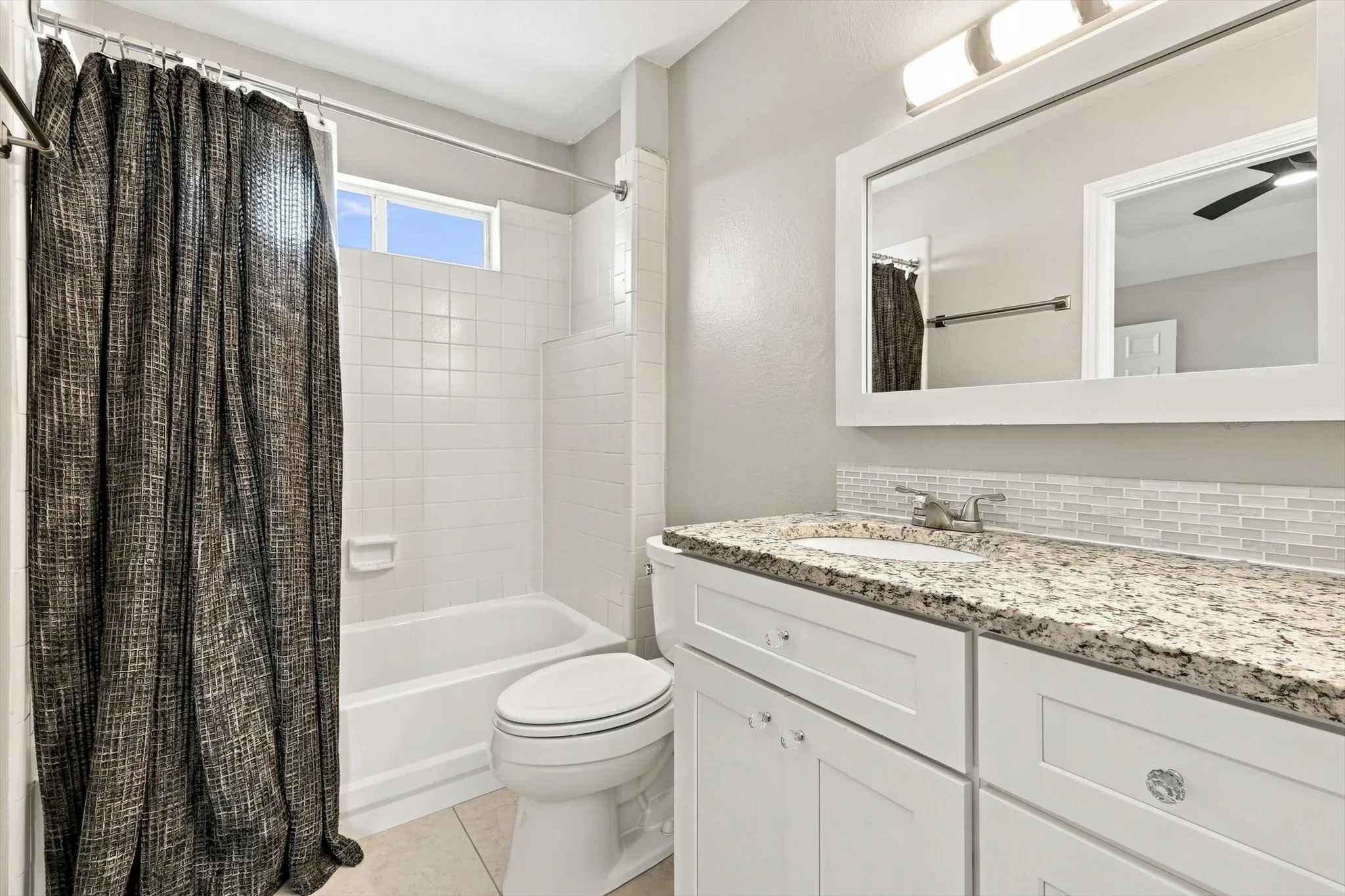 Bathroom featuring a white vanity with a granite-style countertop, undermount sink, and a framed mirror with overhead lighting