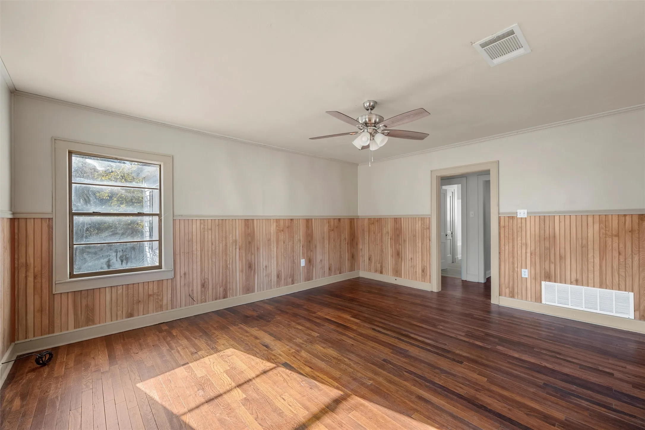 Spacious room featuring wood-finish flooring and wainscoting