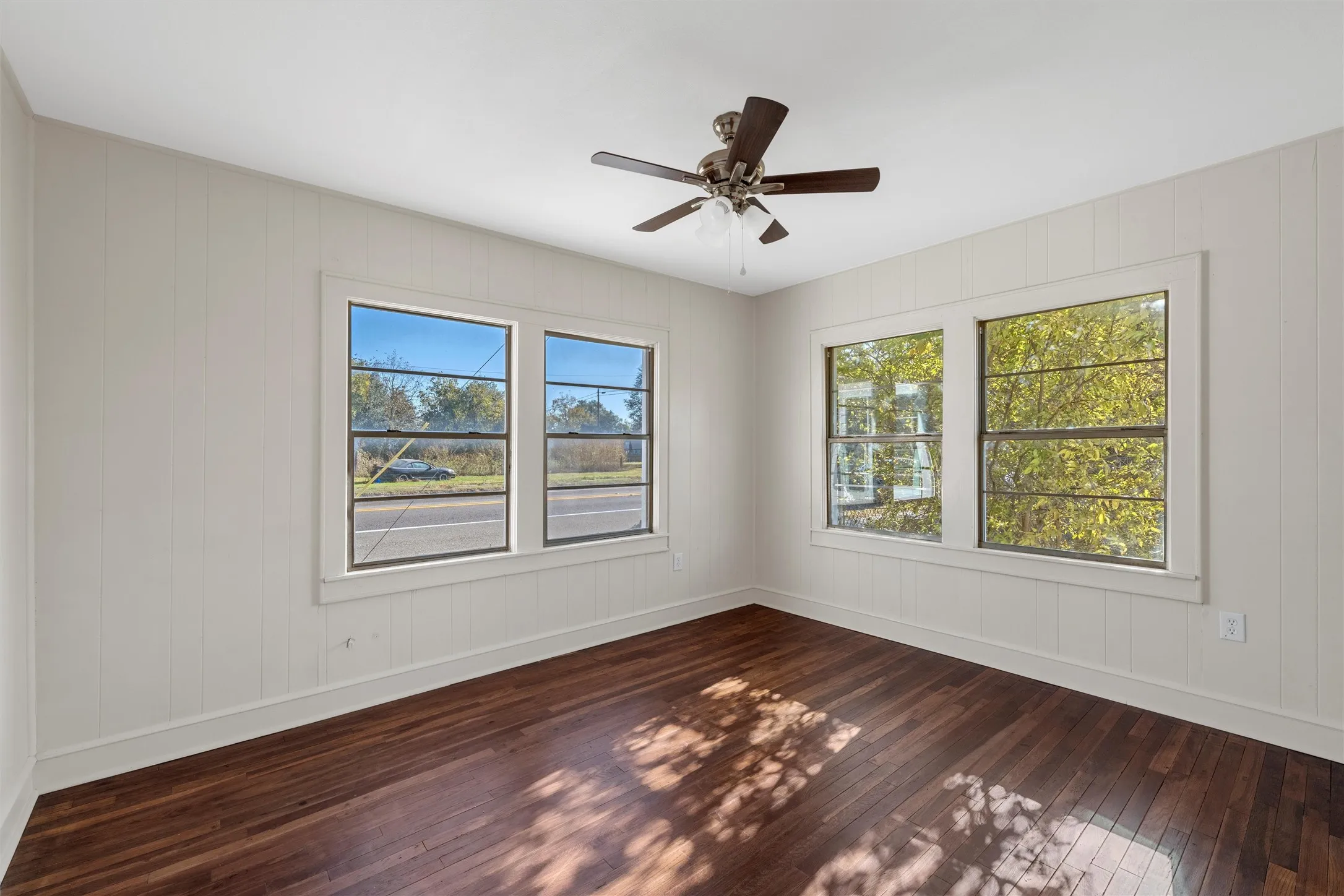 Interior room featuring dark wood-finish flooring and light-toned vertical paneling