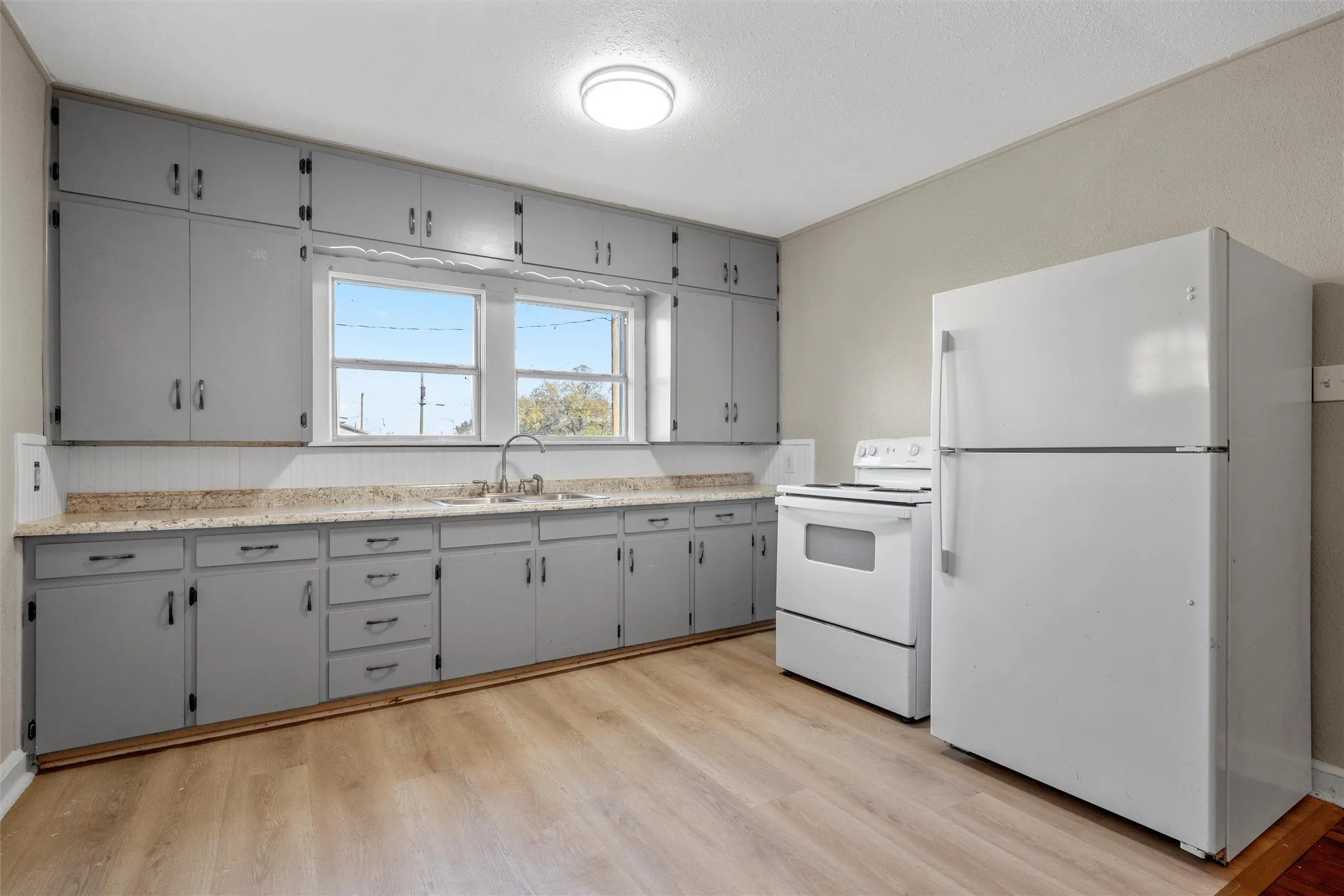 Kitchen featuring light gray cabinetry, light-toned countertops, and wood-finish flooring